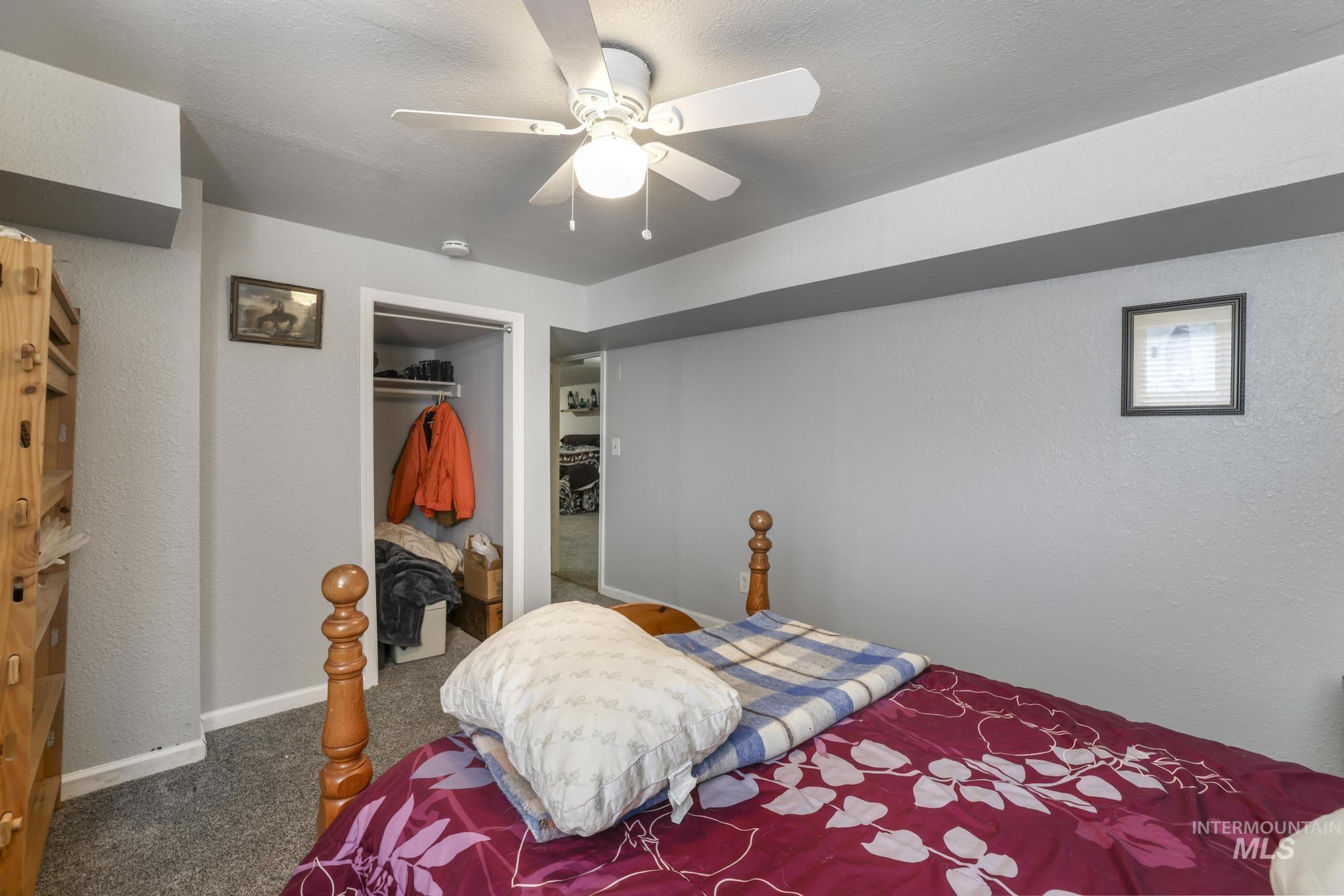 Bedroom featuring a textured wall, dark colored carpet, a ceiling fan, a textured ceiling, and a closet