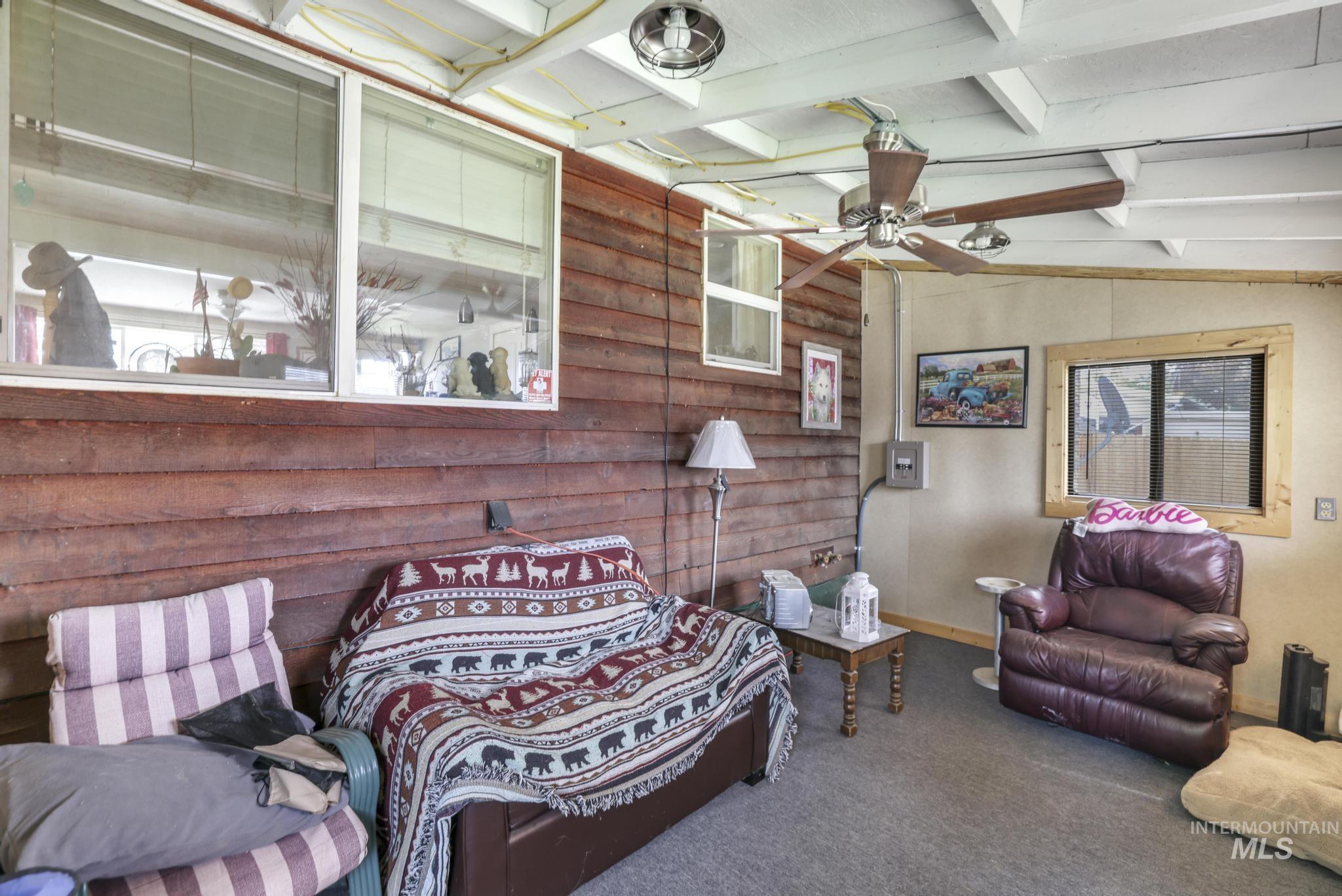 Living room featuring carpet flooring, a ceiling fan, and wood walls