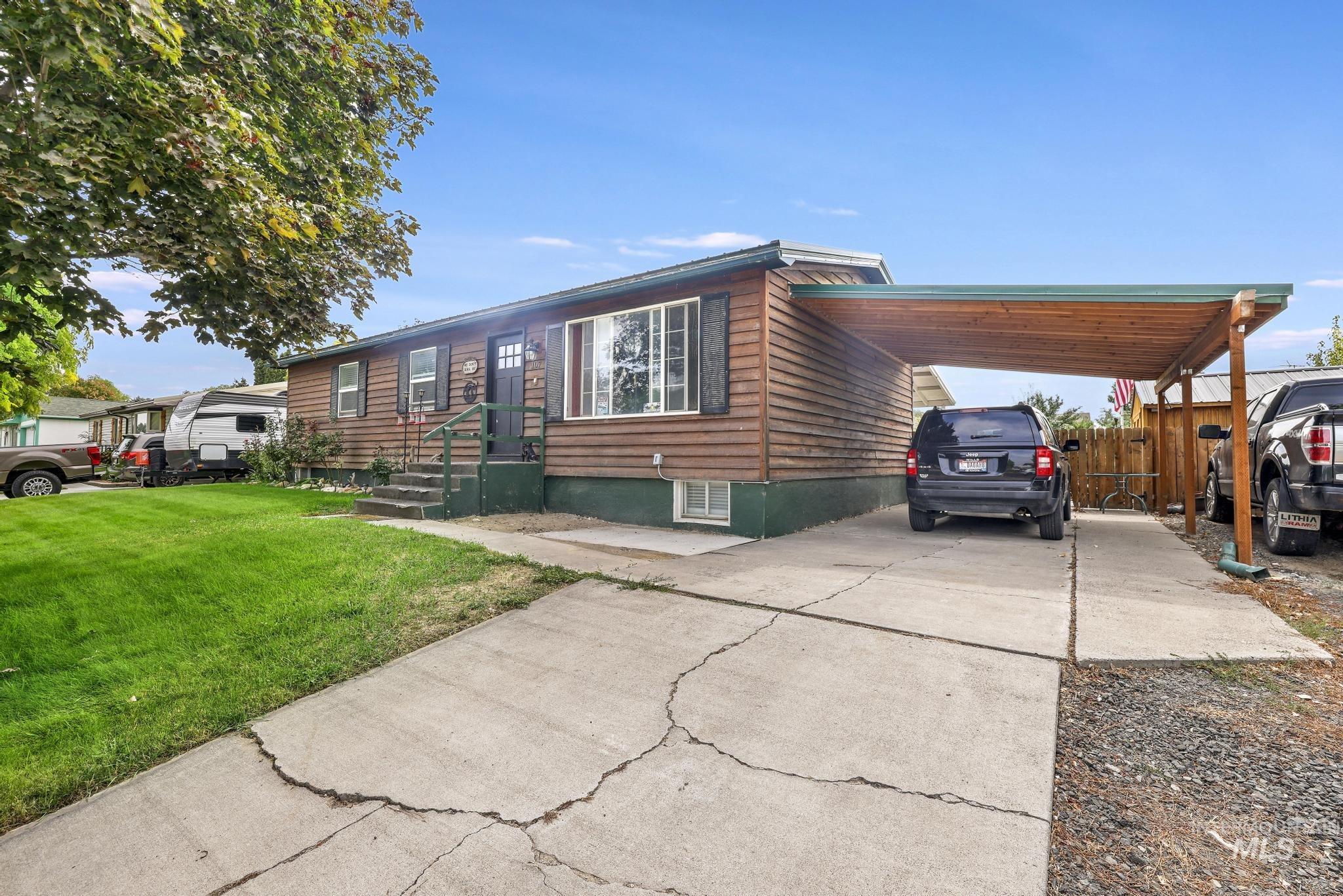 View of front facade with driveway and a carport