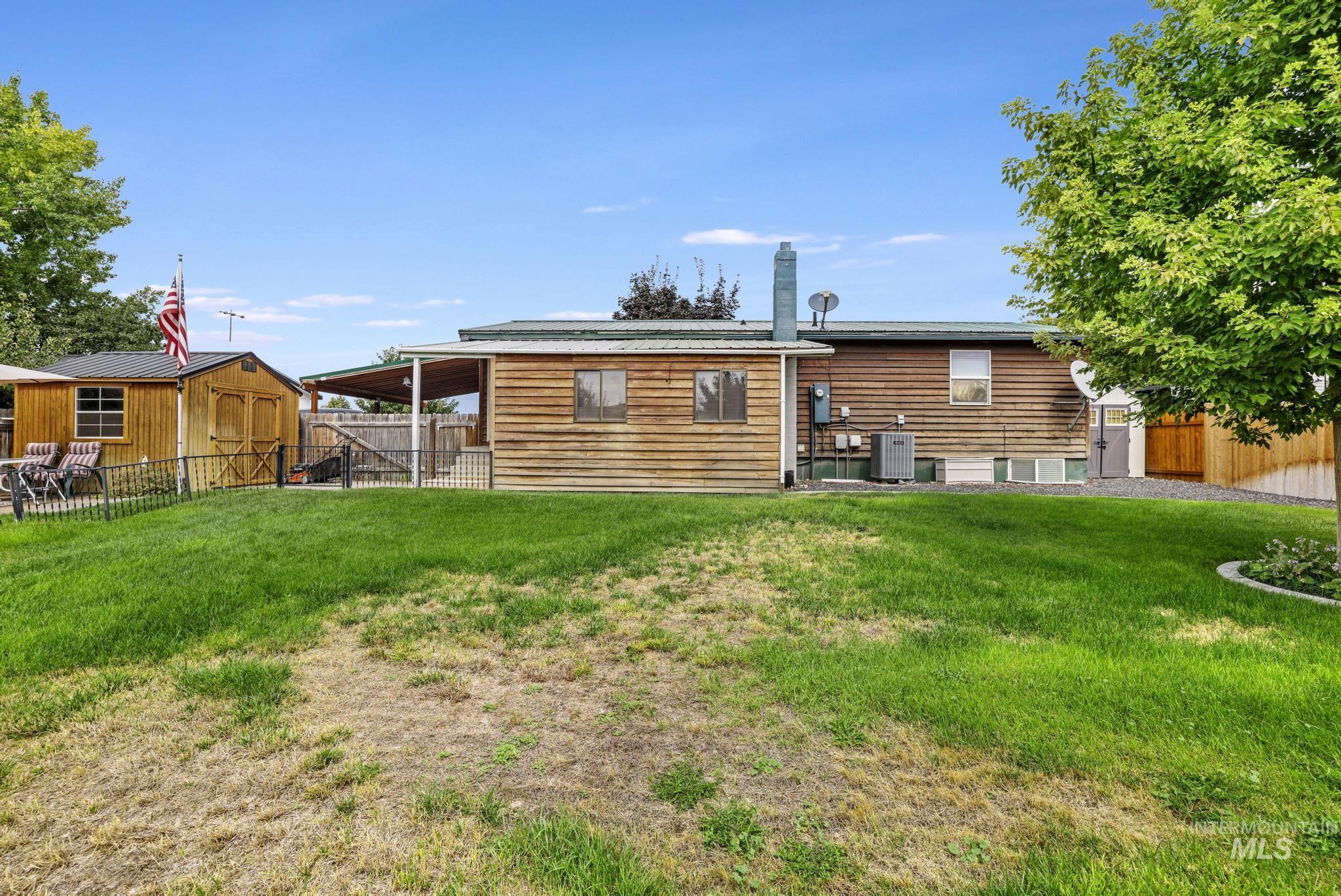 Rear view of house featuring a fenced backyard and a storage unit