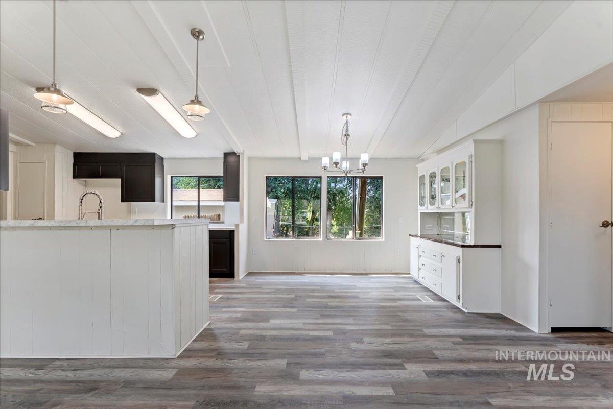Kitchen featuring pendant lighting, dark wood-style flooring, a chandelier, and white cabinetry