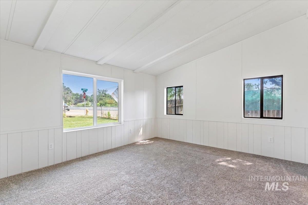Empty room with carpet flooring, a wainscoted wall, and a decorative wall