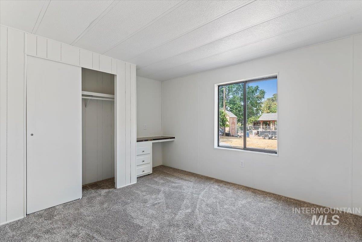 Unfurnished bedroom featuring carpet, a closet, and built in desk