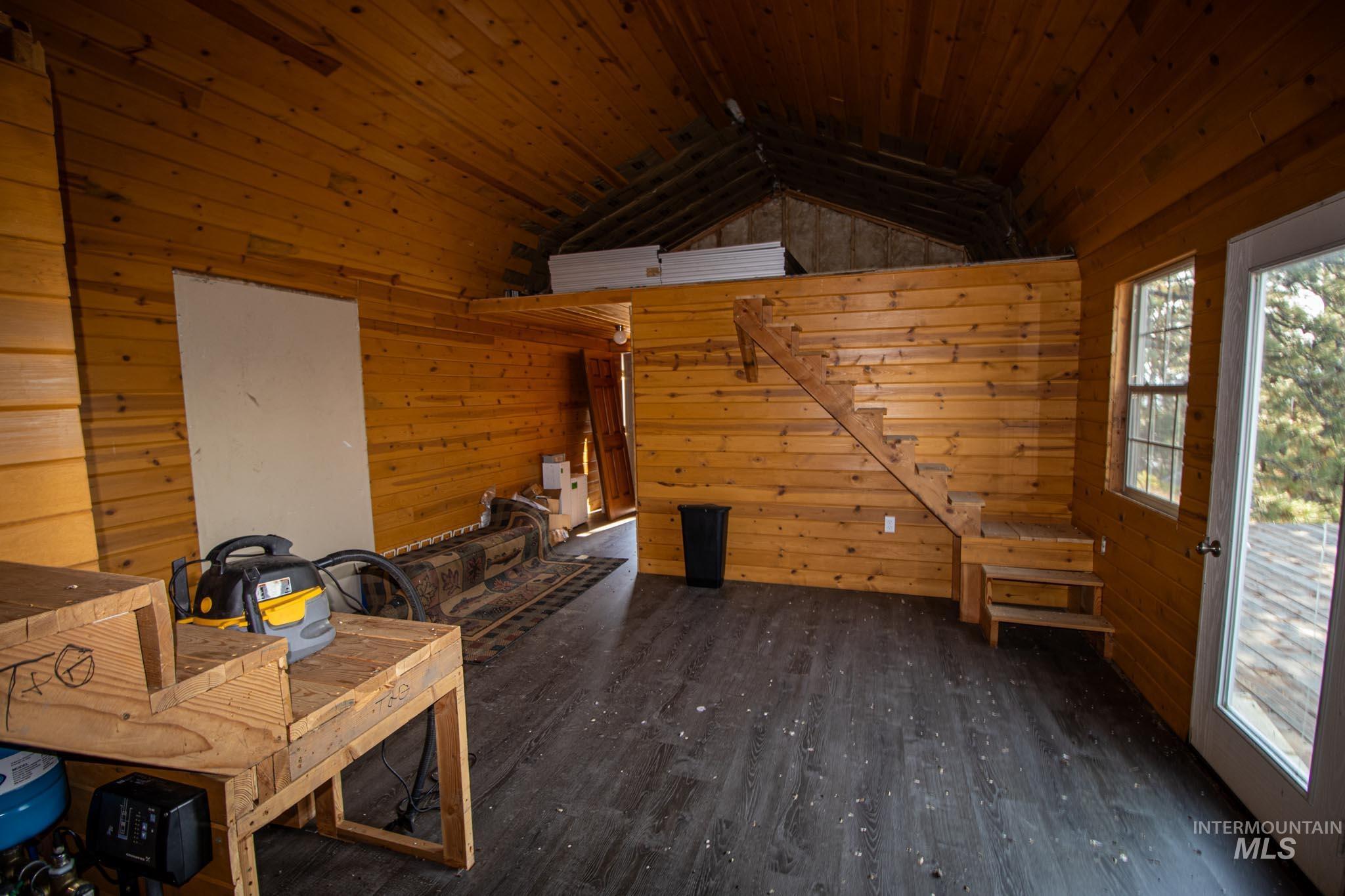 Interior space featuring wood walls, dark wood-type flooring, and lofted ceiling