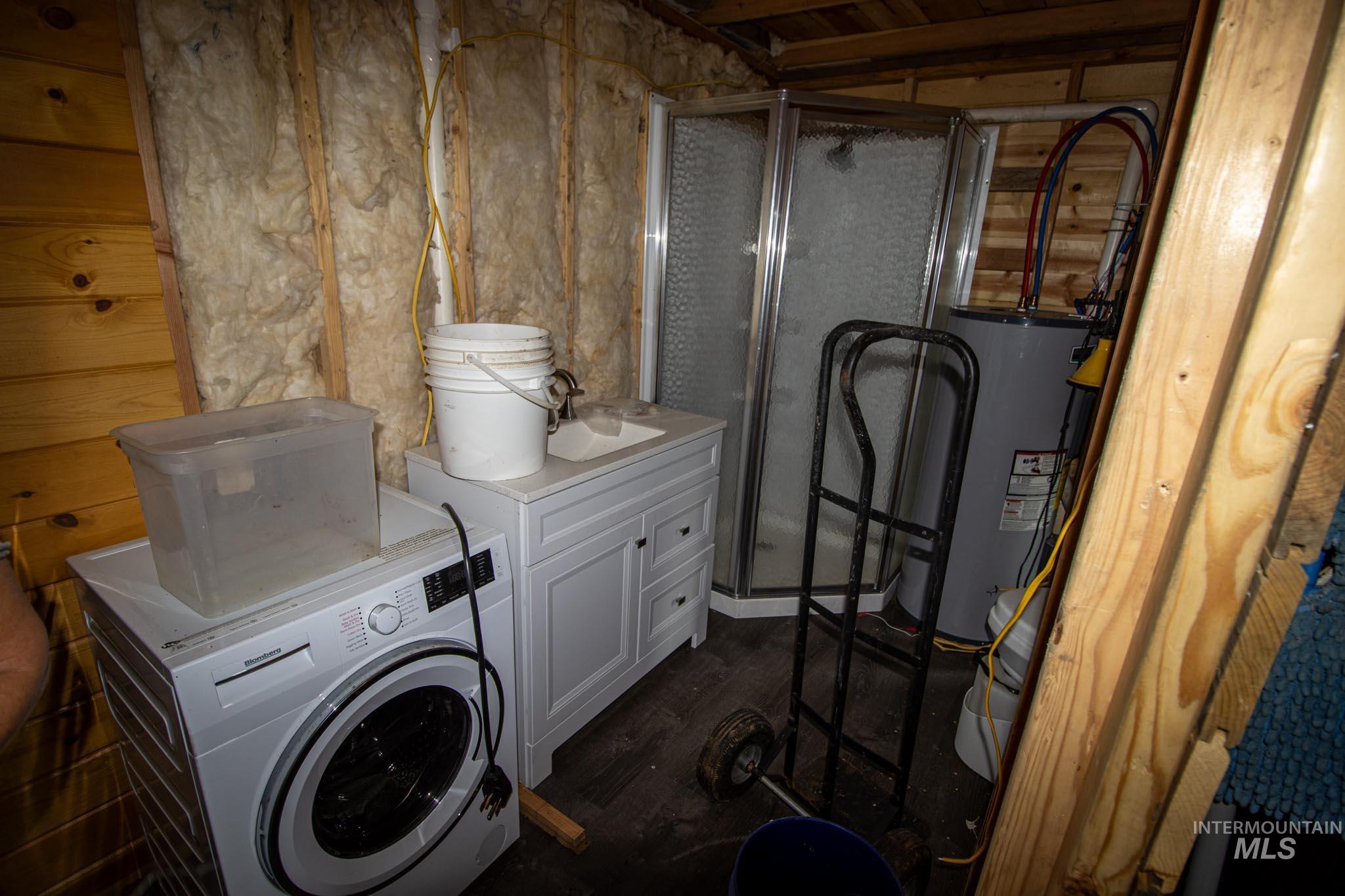 Laundry area featuring washer / dryer, water heater, and dark wood-type flooring