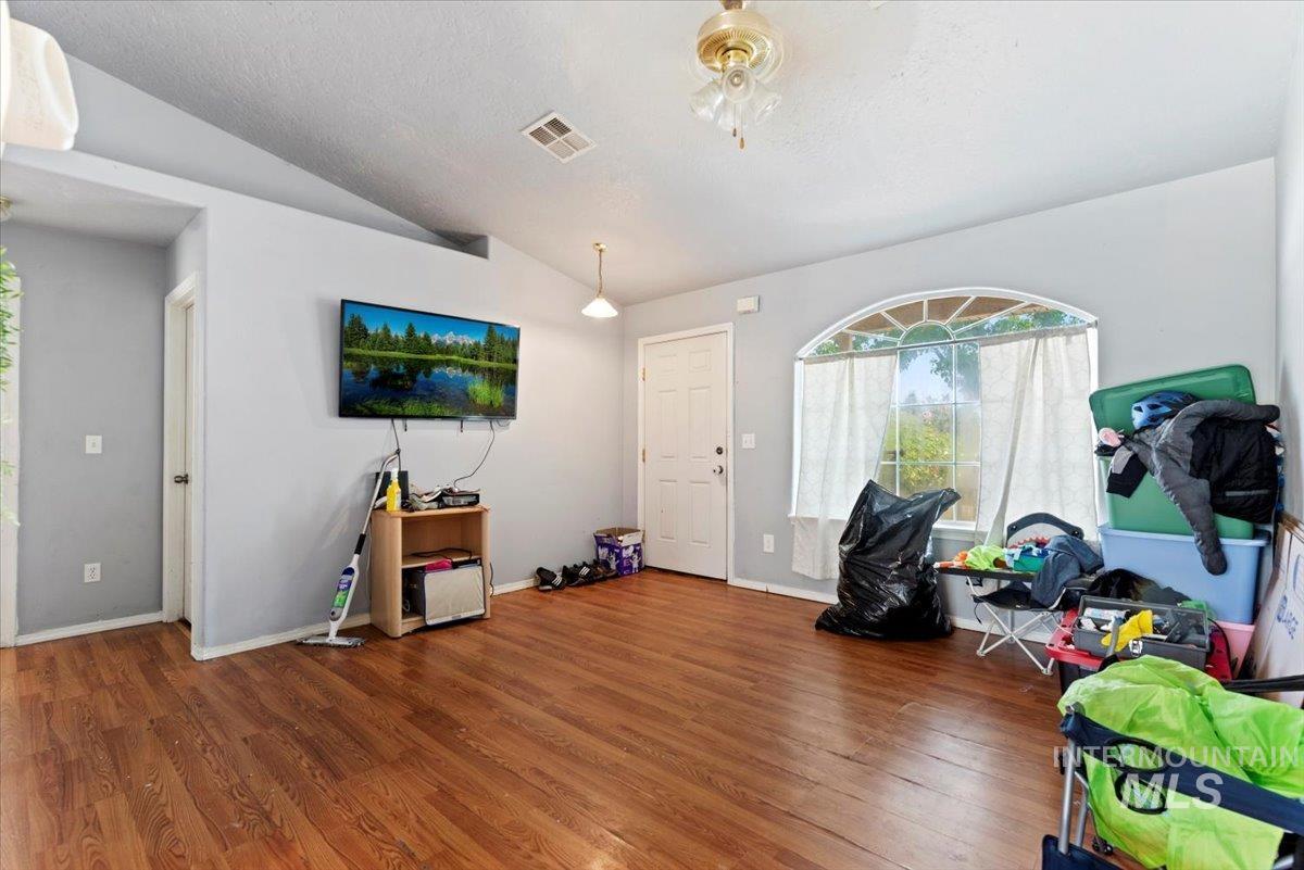 Recreation room featuring vaulted ceiling, wood finished floors, and a textured ceiling