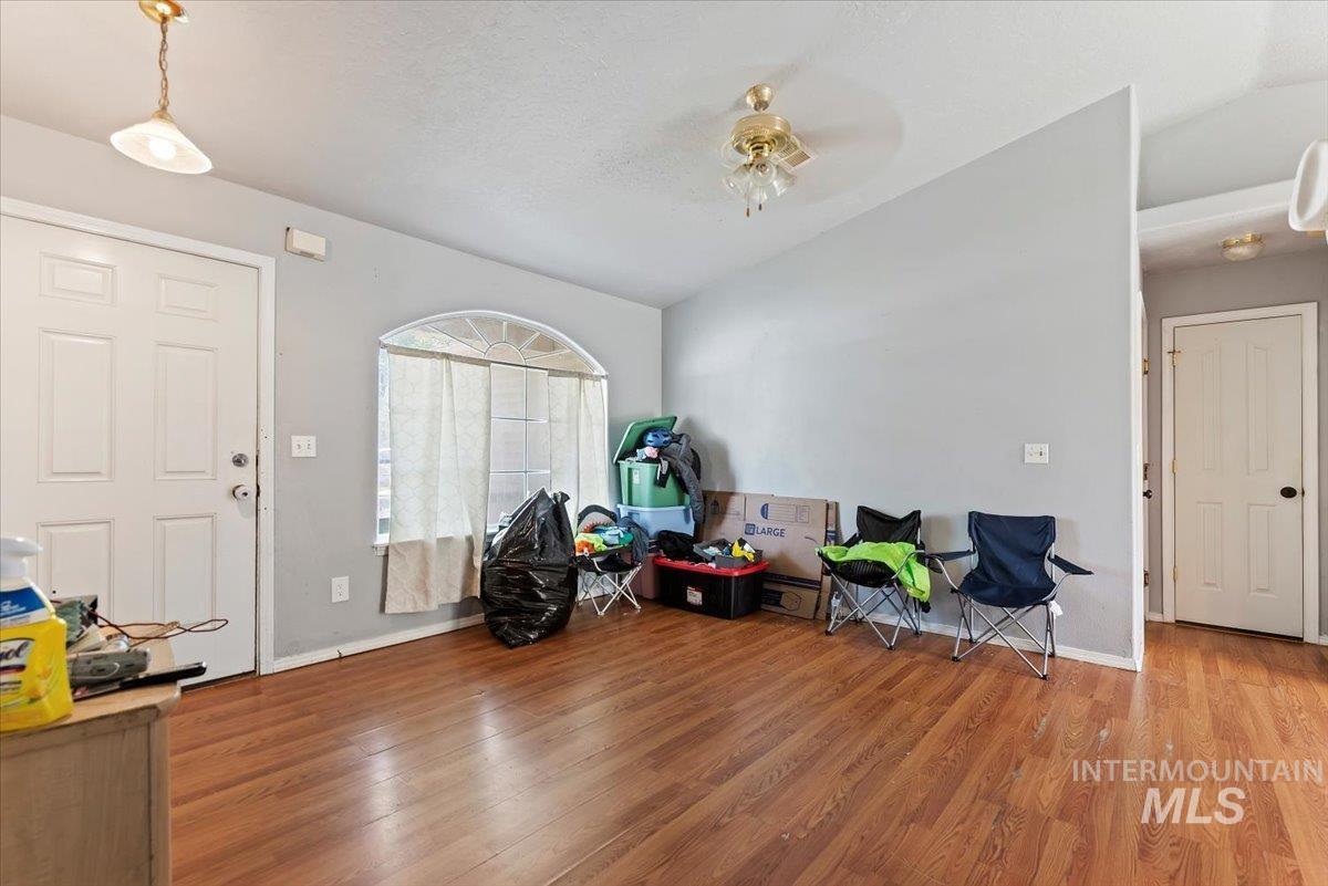 Entryway with wood finished floors, vaulted ceiling, ceiling fan, and a textured ceiling