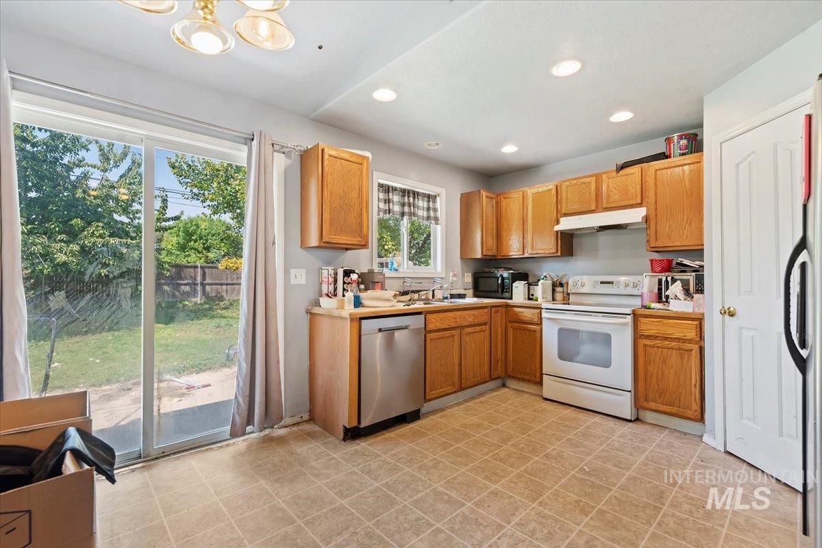Kitchen featuring white appliances, recessed lighting, light countertops, and under cabinet range hood