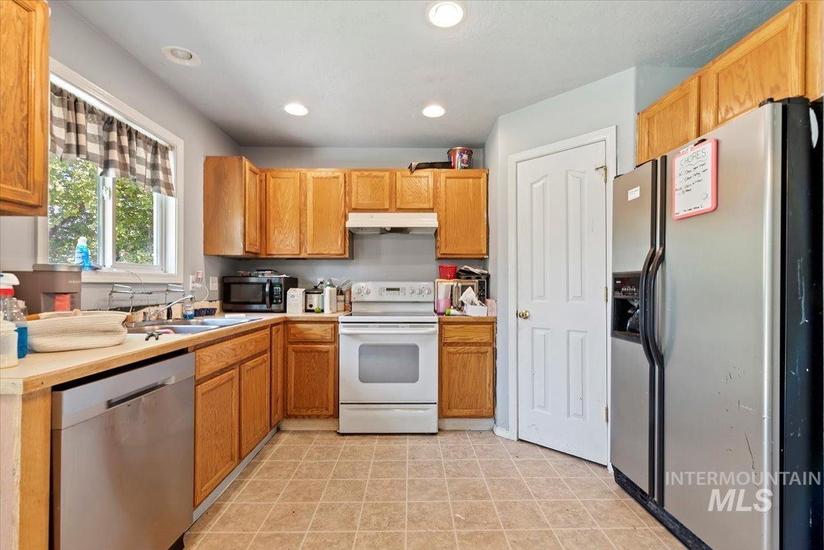 Kitchen with appliances with stainless steel finishes, light countertops, recessed lighting, and under cabinet range hood