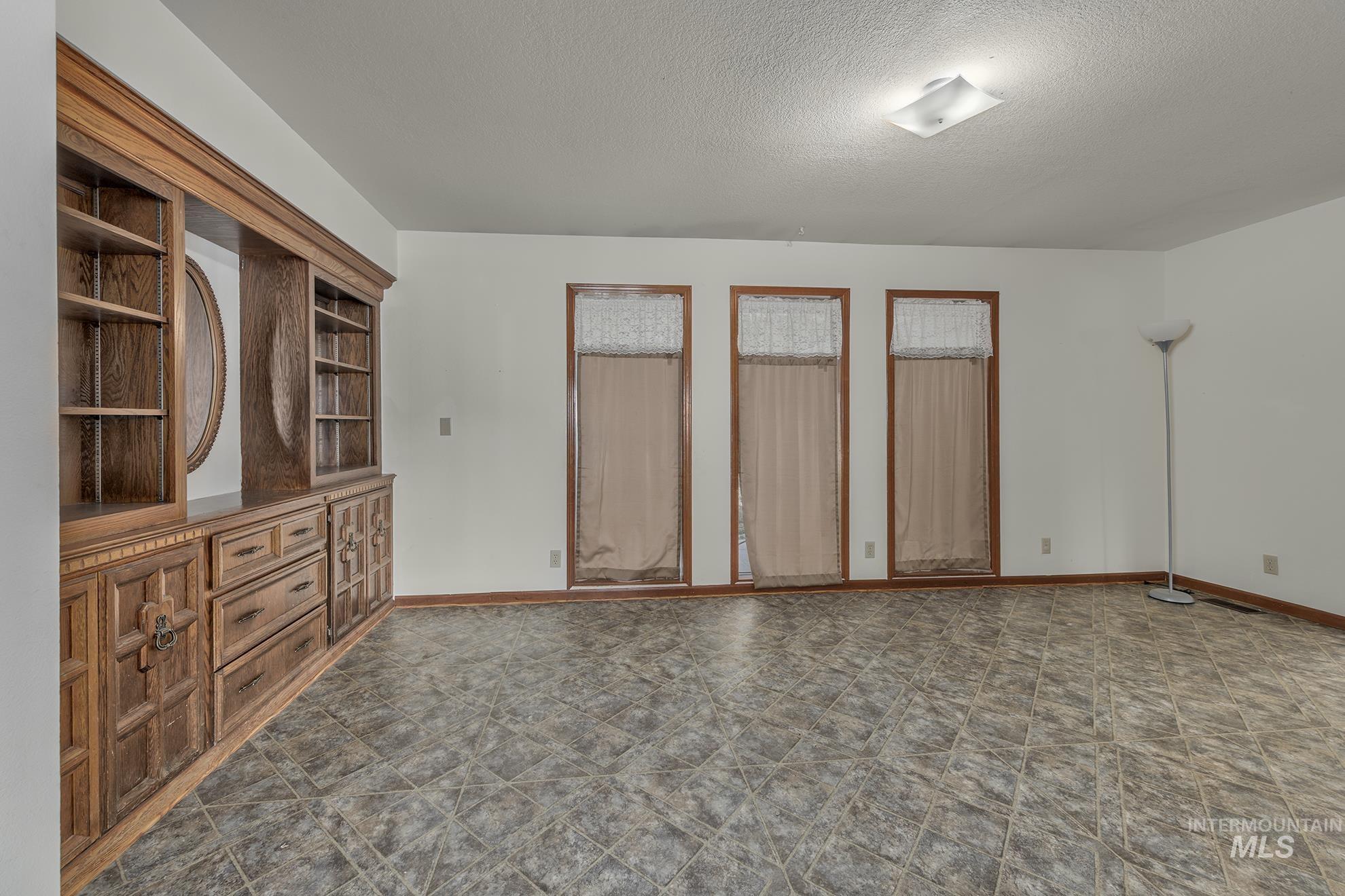 Unfurnished room with baseboards and a textured ceiling