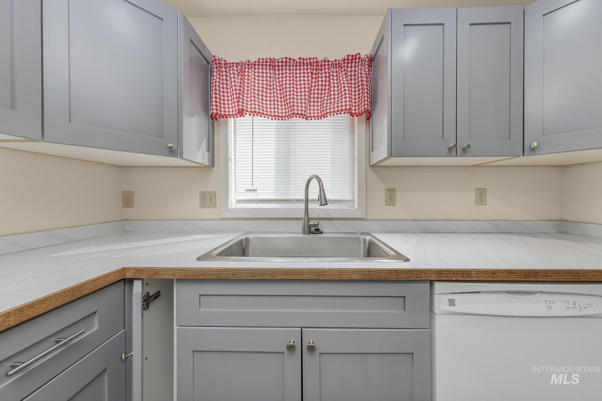 Kitchen featuring dishwasher, gray cabinetry, and light countertops