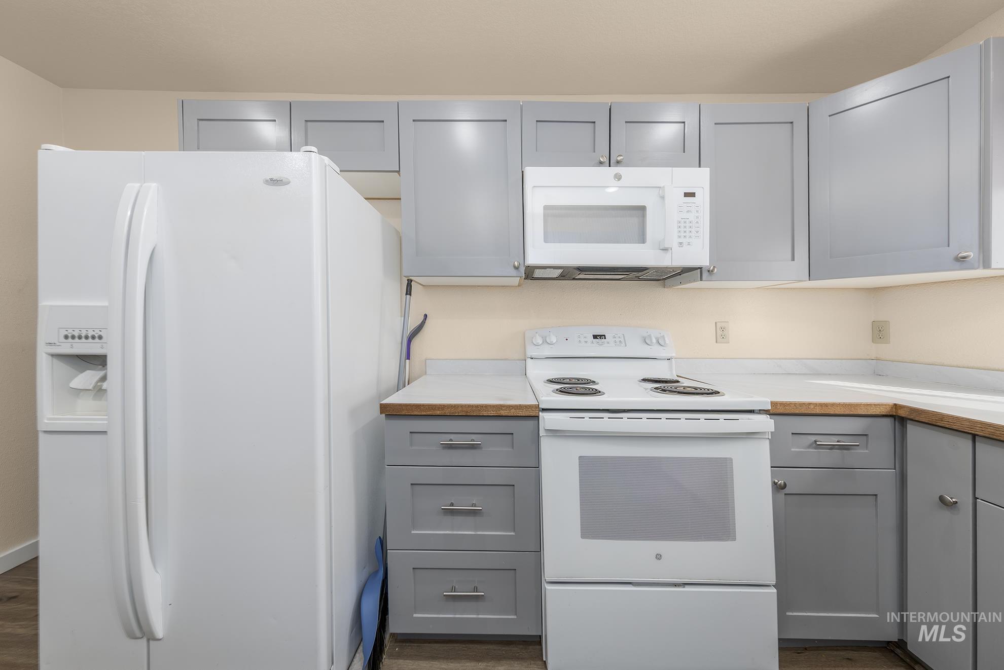 Kitchen featuring gray cabinetry, white appliances, and light countertops