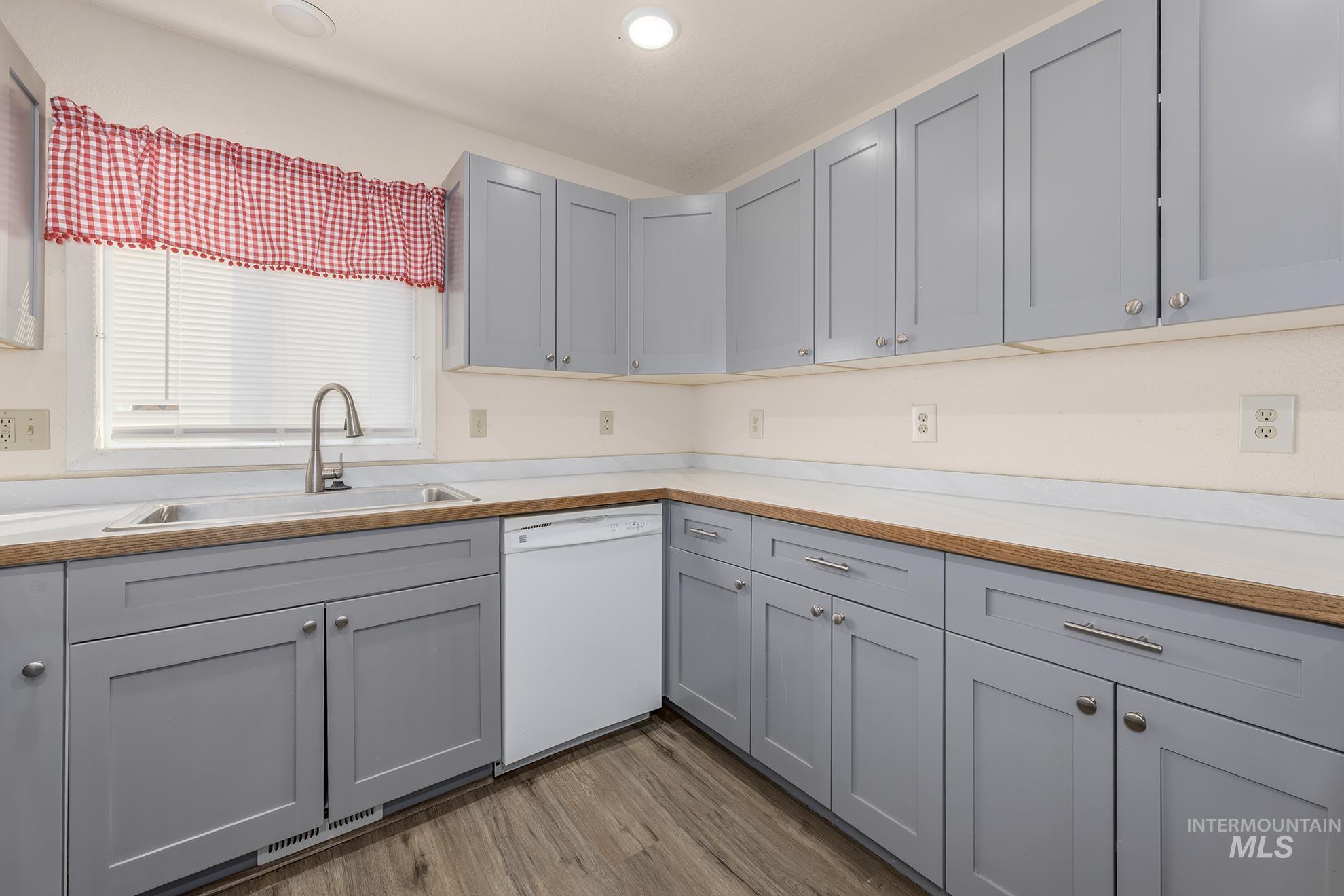 Kitchen featuring gray cabinetry, light countertops, white dishwasher, light wood finished floors, and recessed lighting