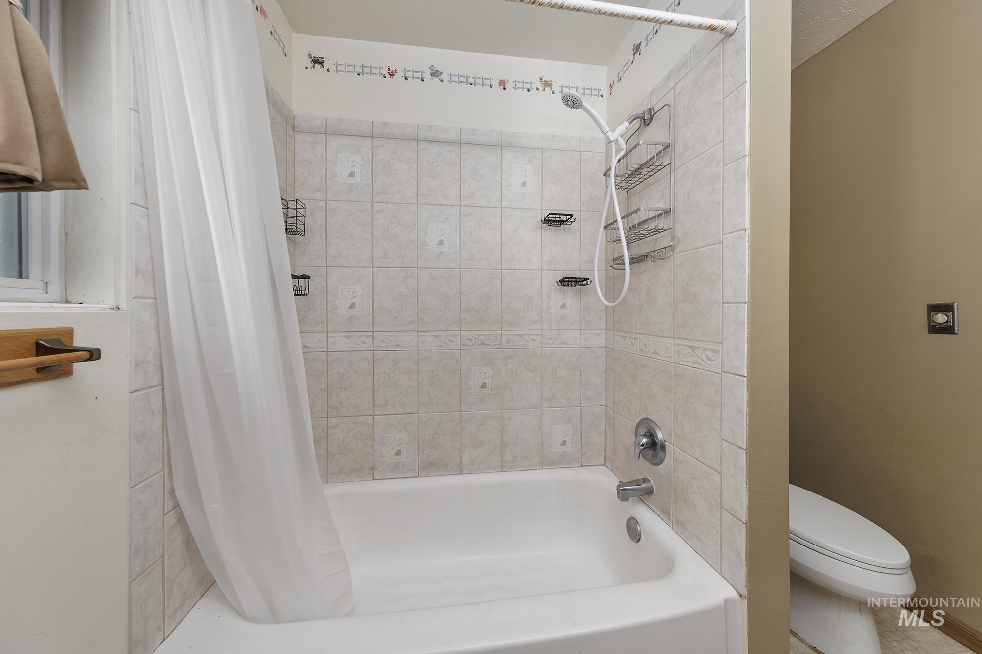 Bathroom featuring toilet and shower / bath combo with shower curtain