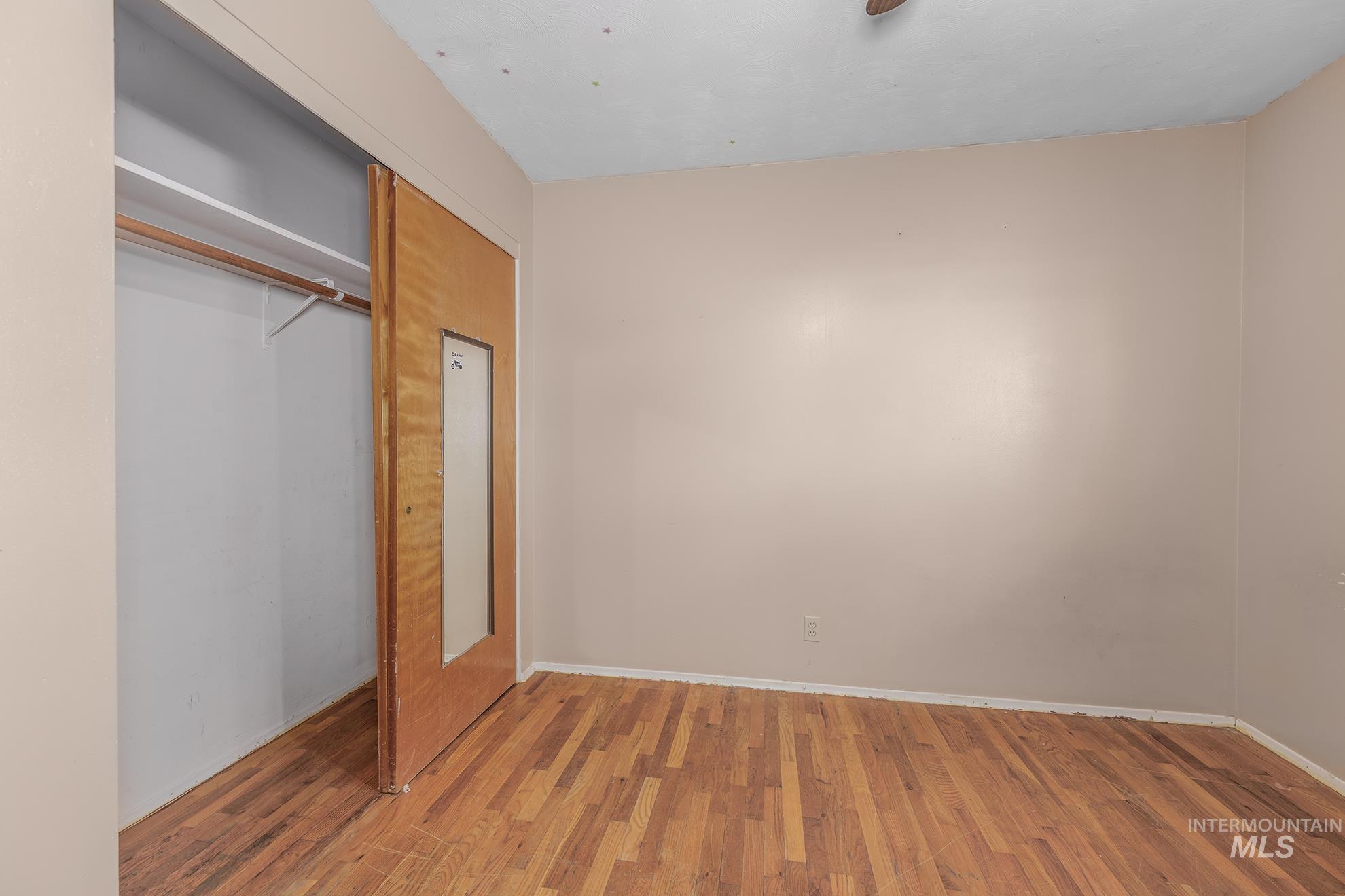 Unfurnished bedroom featuring wood finished floors and a closet