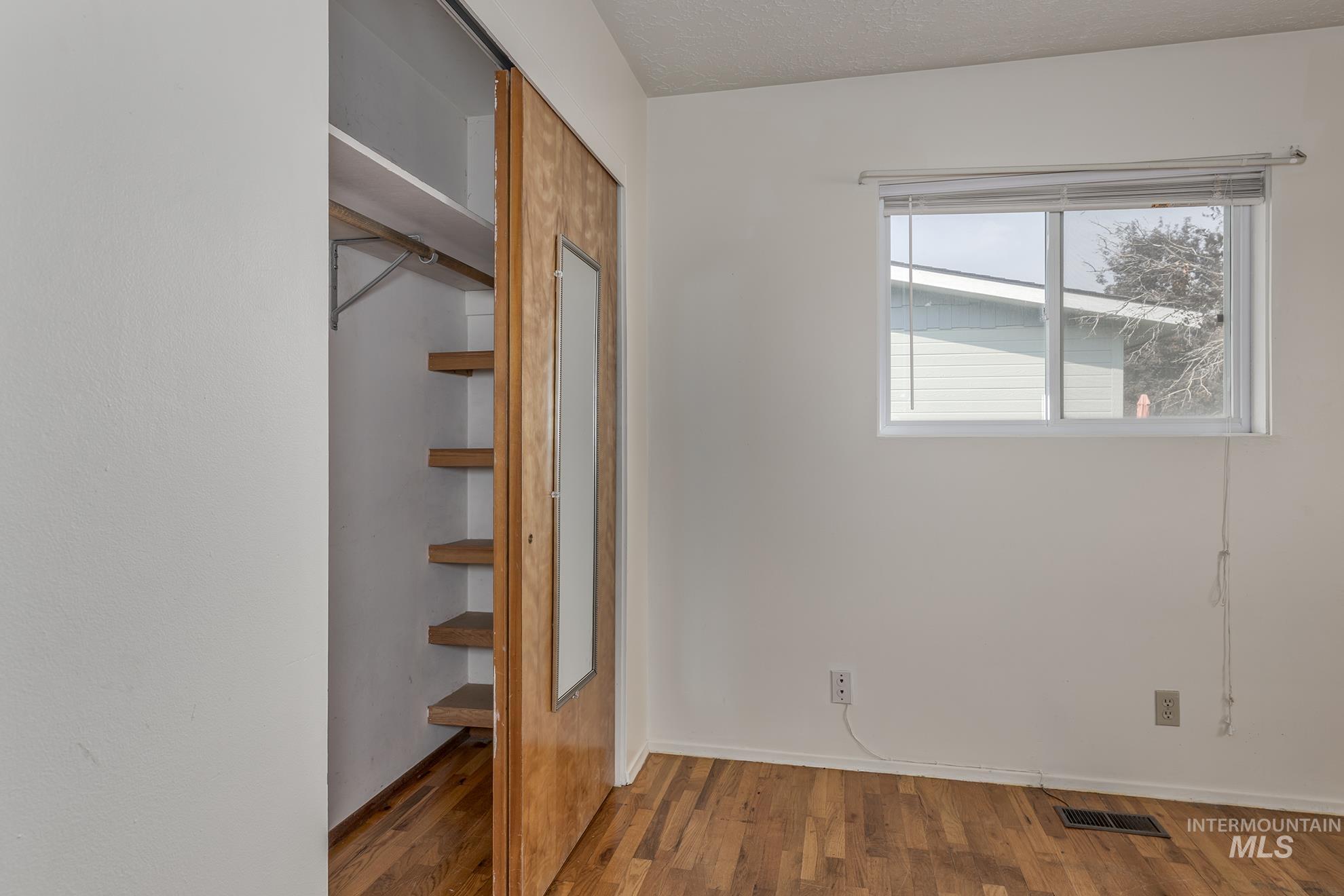 Unfurnished bedroom featuring wood finished floors, a closet, and a textured ceiling