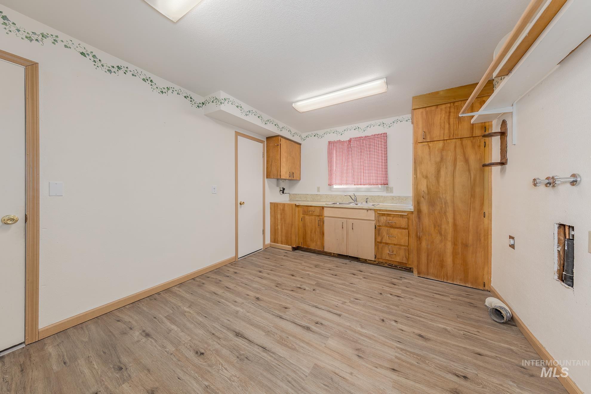 Laundry room with light wood-style flooring and cabinet space