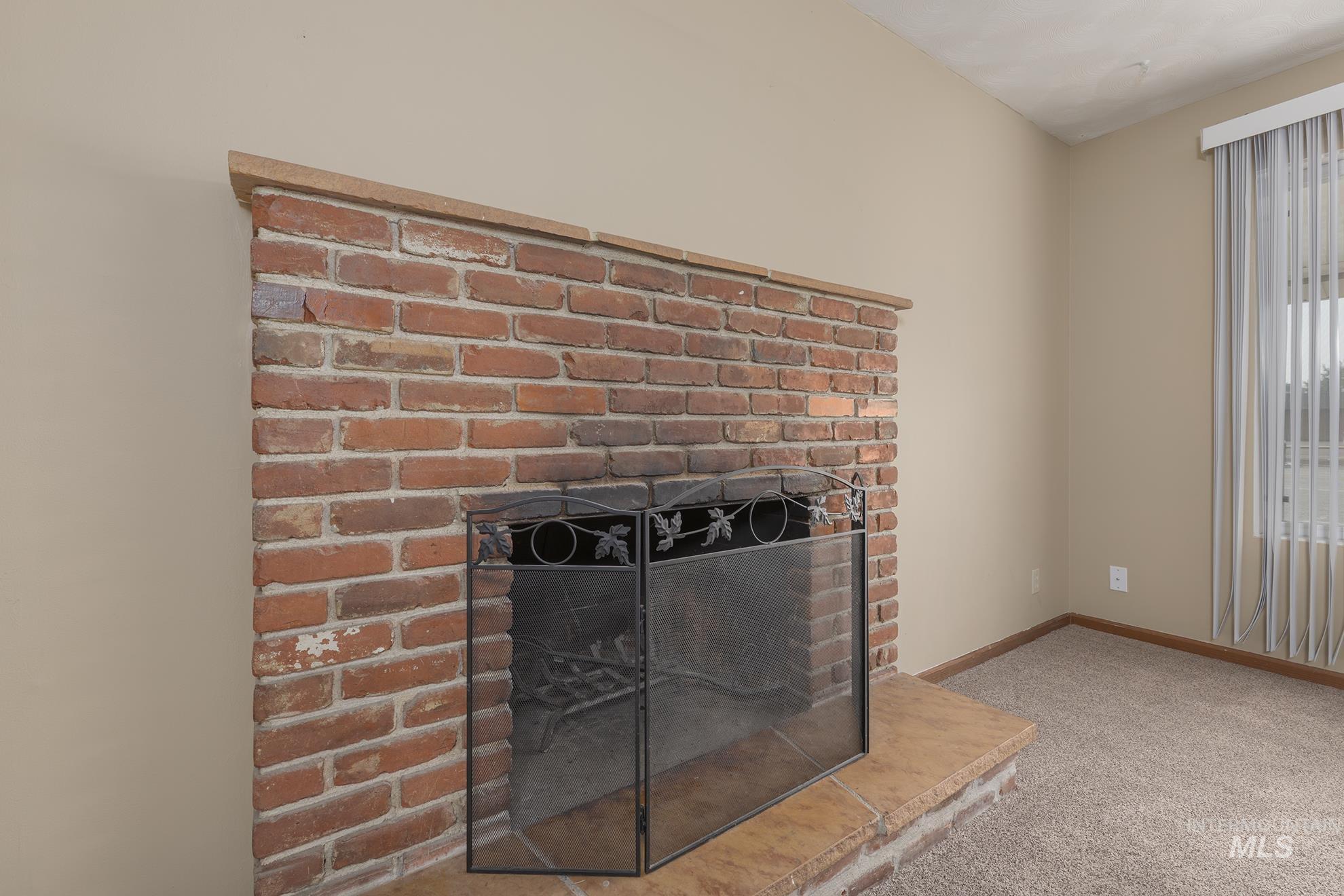 Detailed view of a brick fireplace and carpet flooring