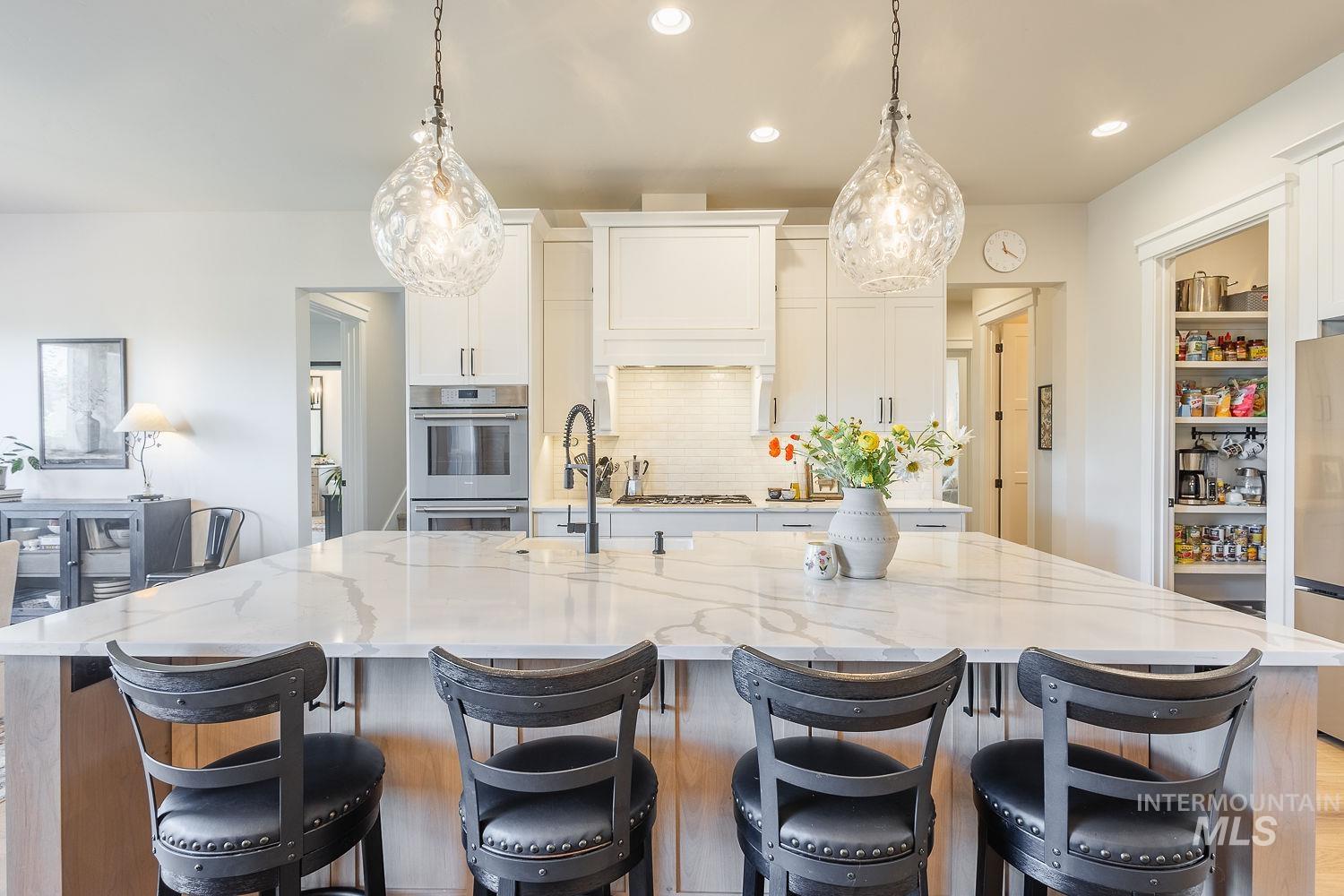 Kitchen featuring appliances with stainless steel finishes, a spacious island, light stone counters, white cabinetry, and recessed lighting