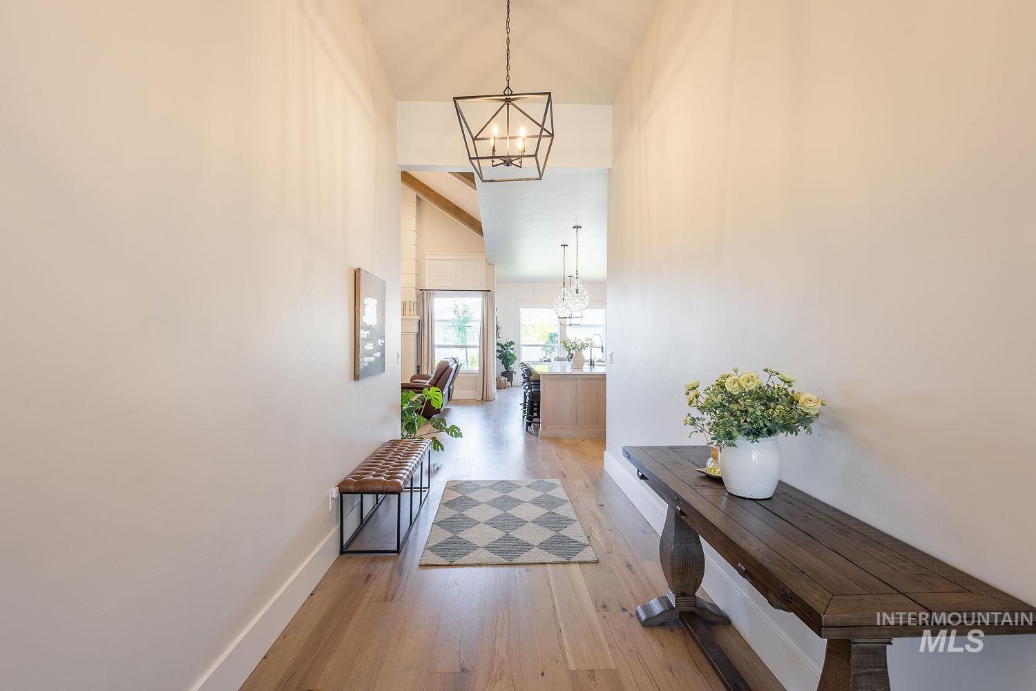 Hallway with a chandelier, light wood finished floors, and high vaulted ceiling