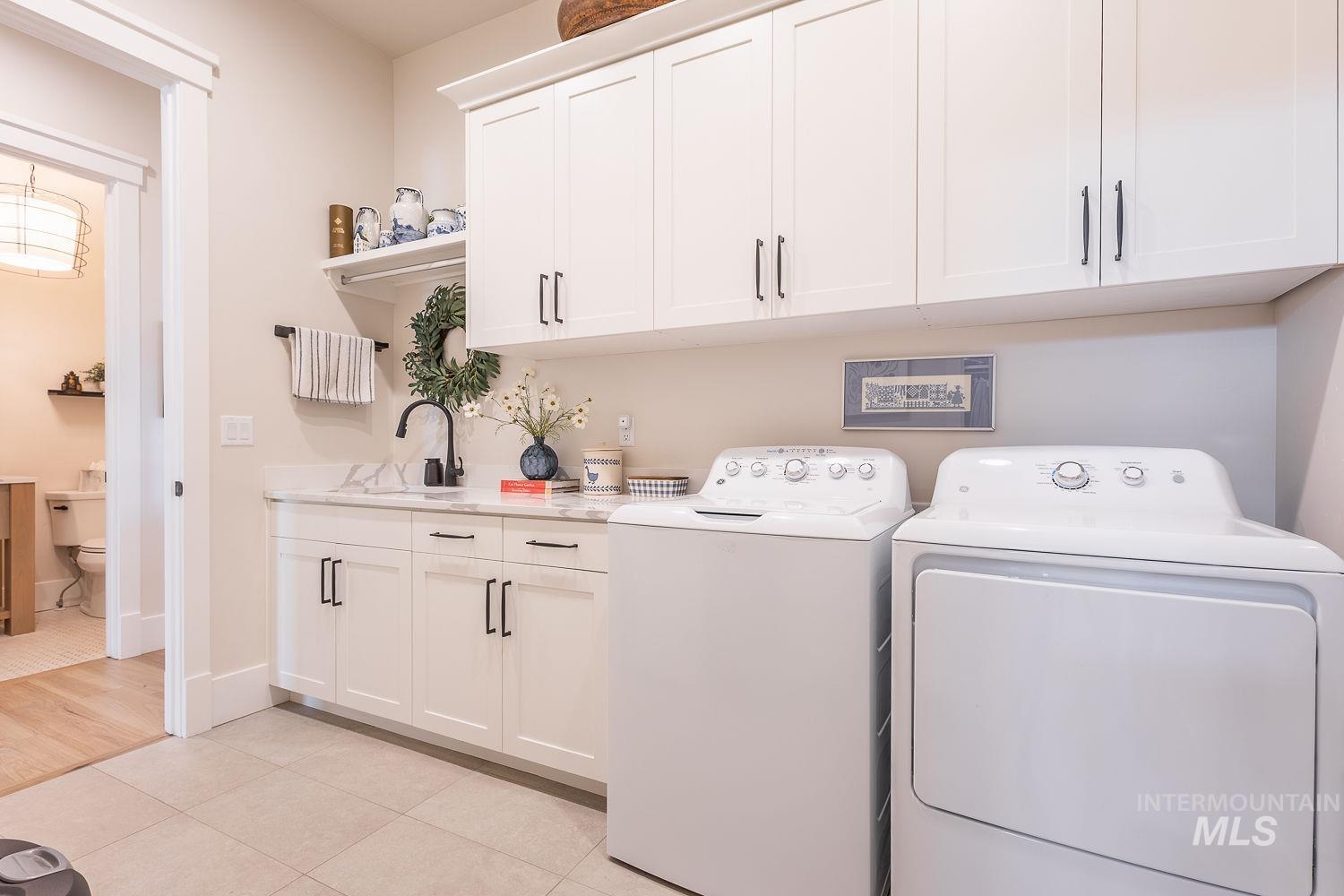 Laundry room featuring washer and dryer, cabinet space, and light tile patterned floors