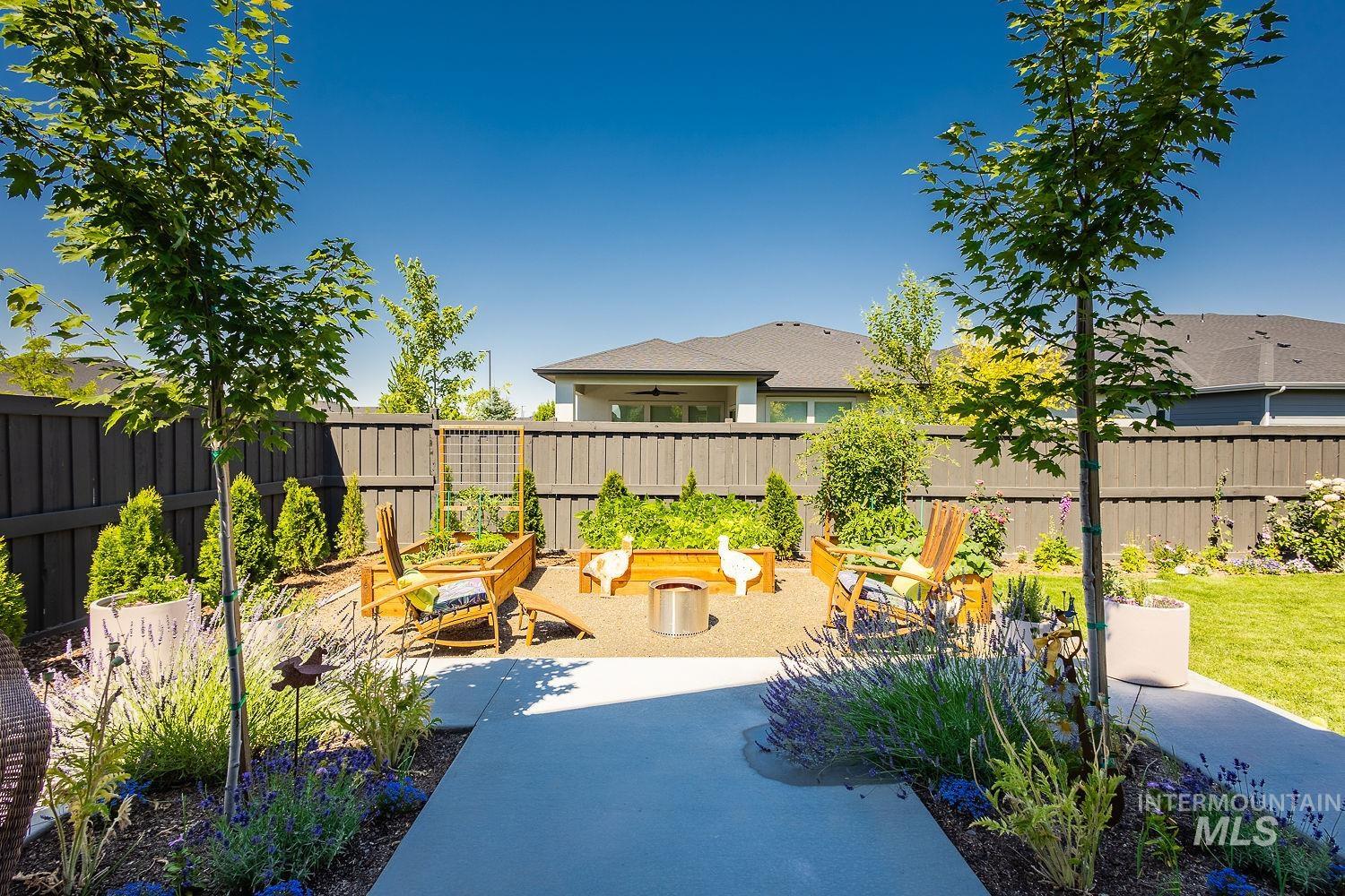 Fenced backyard with a patio area and a vegetable garden
