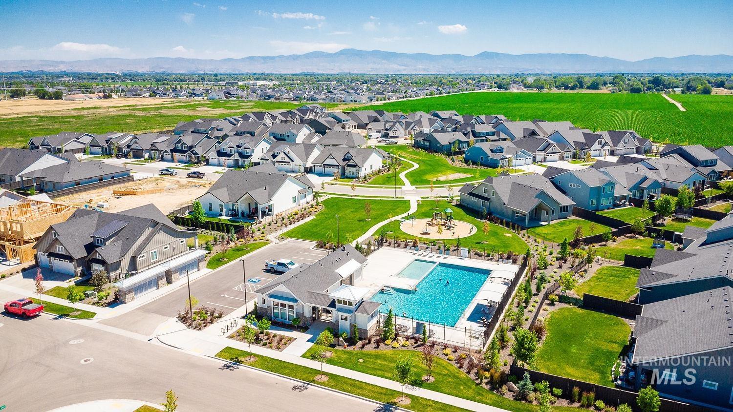 Aerial perspective of suburban area featuring a mountain backdrop and a pool
