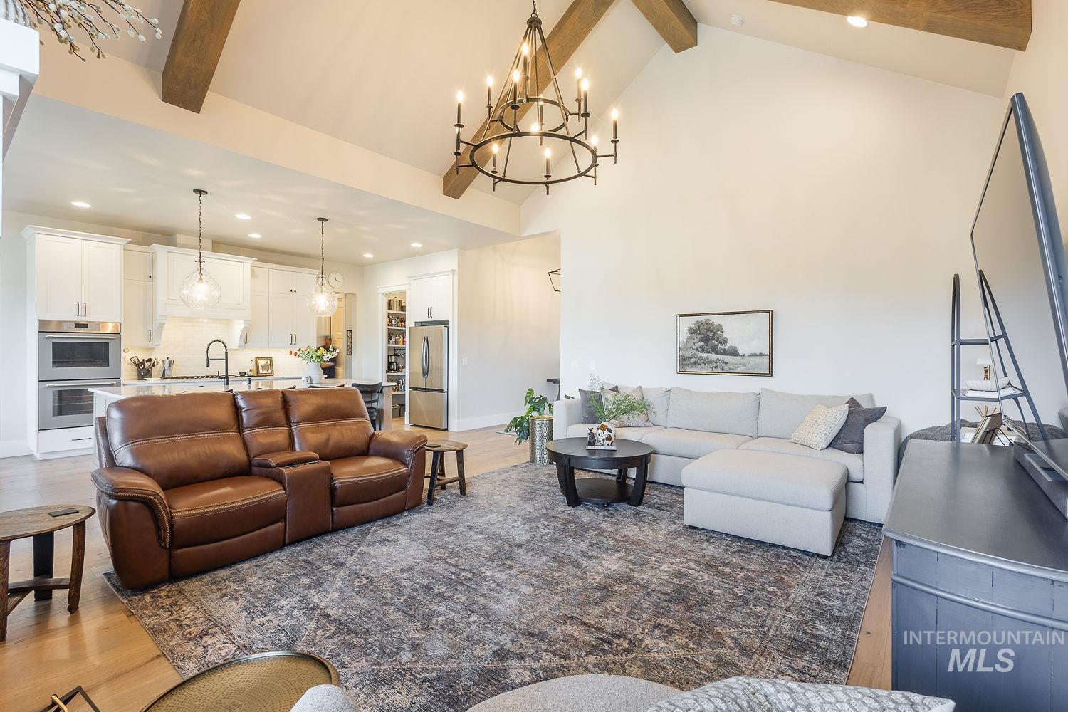 Living area featuring beam ceiling, recessed lighting, wood finished floors, high vaulted ceiling, and a chandelier