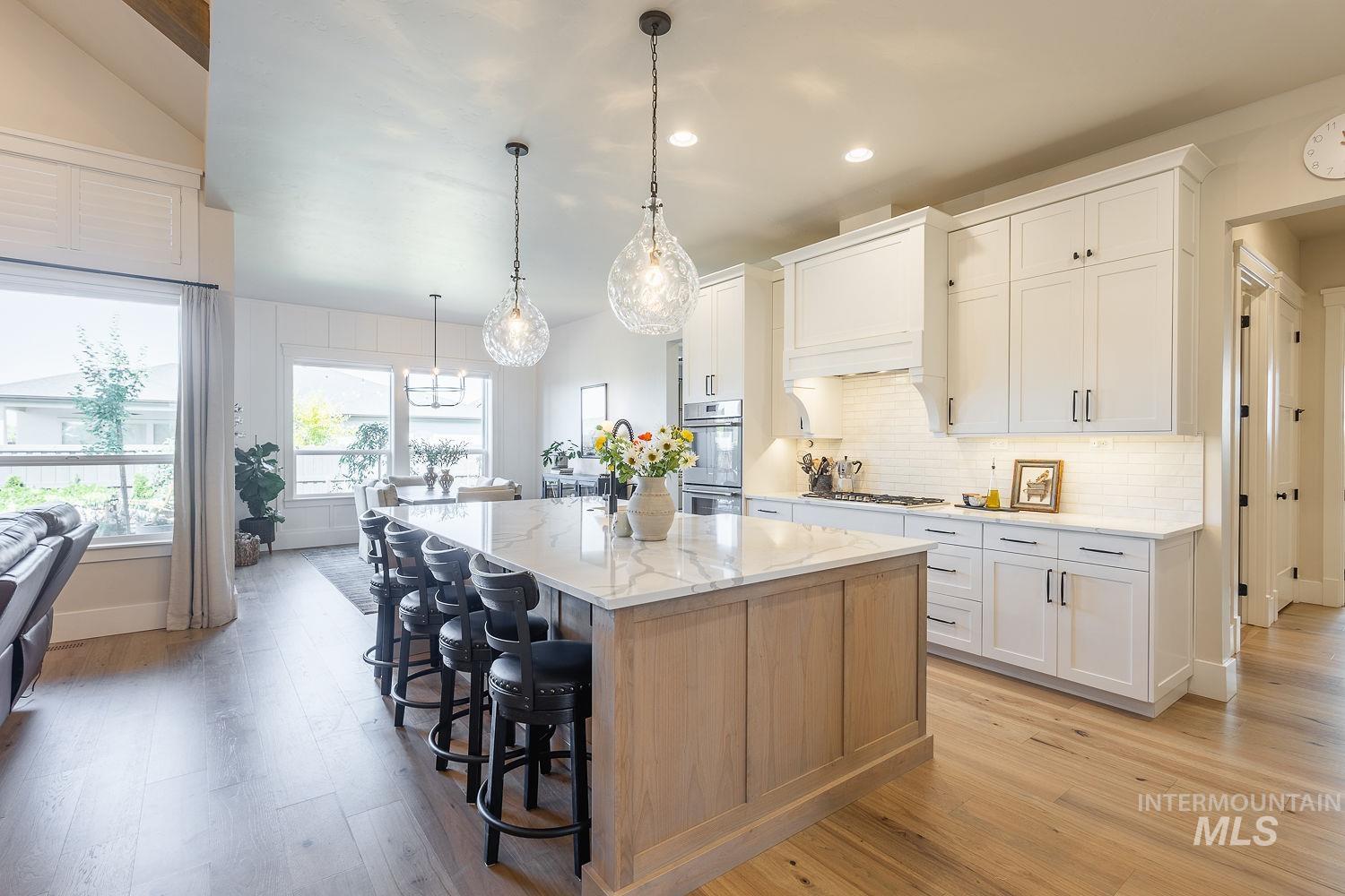 Kitchen featuring stainless steel appliances, light wood-style flooring, a kitchen bar, a center island, and recessed lighting