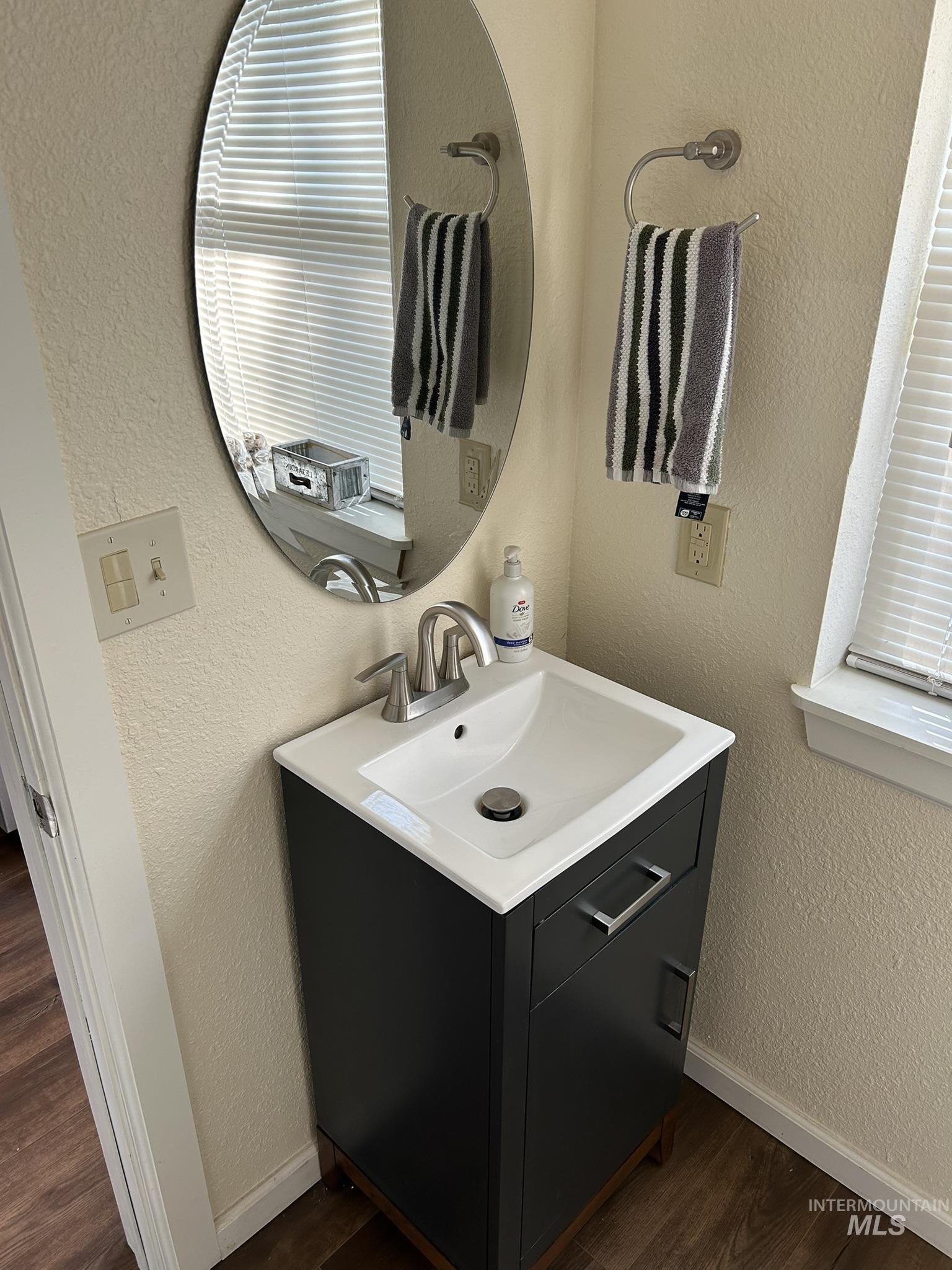 Bathroom featuring a textured wall, dark wood-type flooring, and vanity