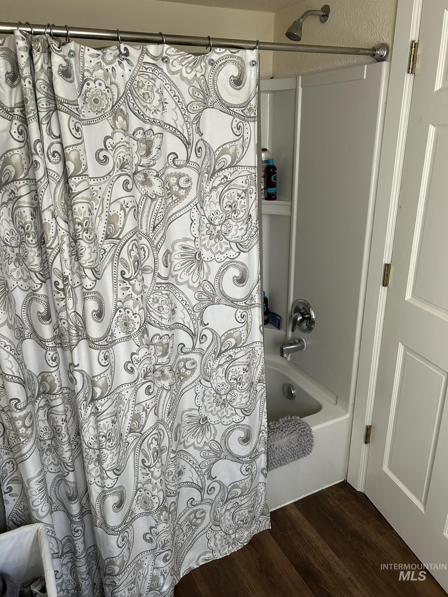 Full bath featuring dark wood-style floors and shower / bath combo