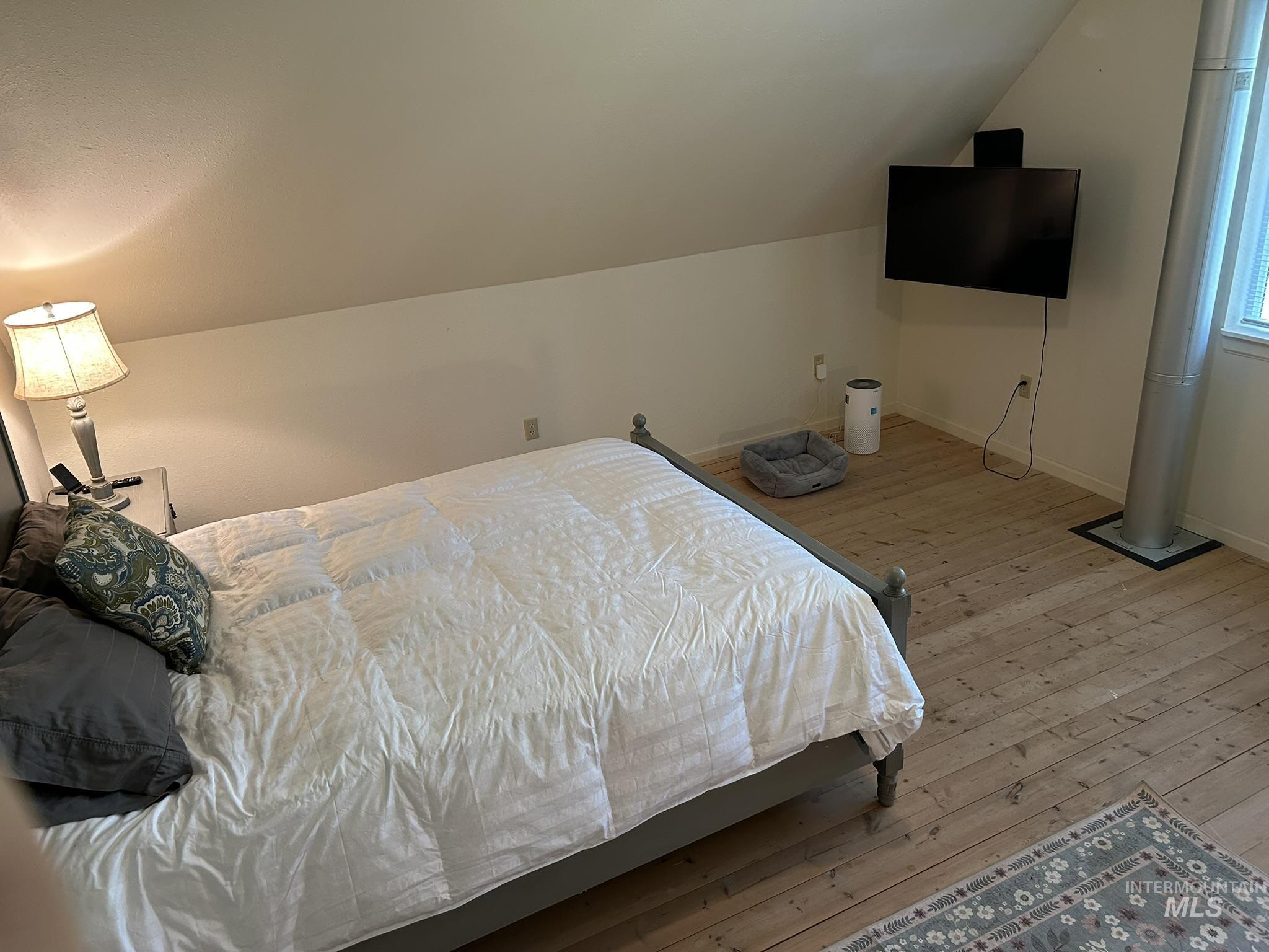 Bedroom featuring light wood-type flooring and lofted ceiling