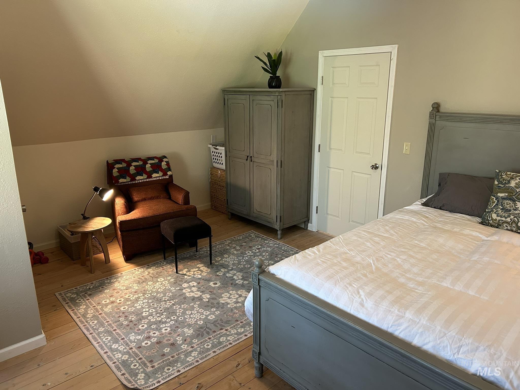 Bedroom with wood-type flooring and vaulted ceiling