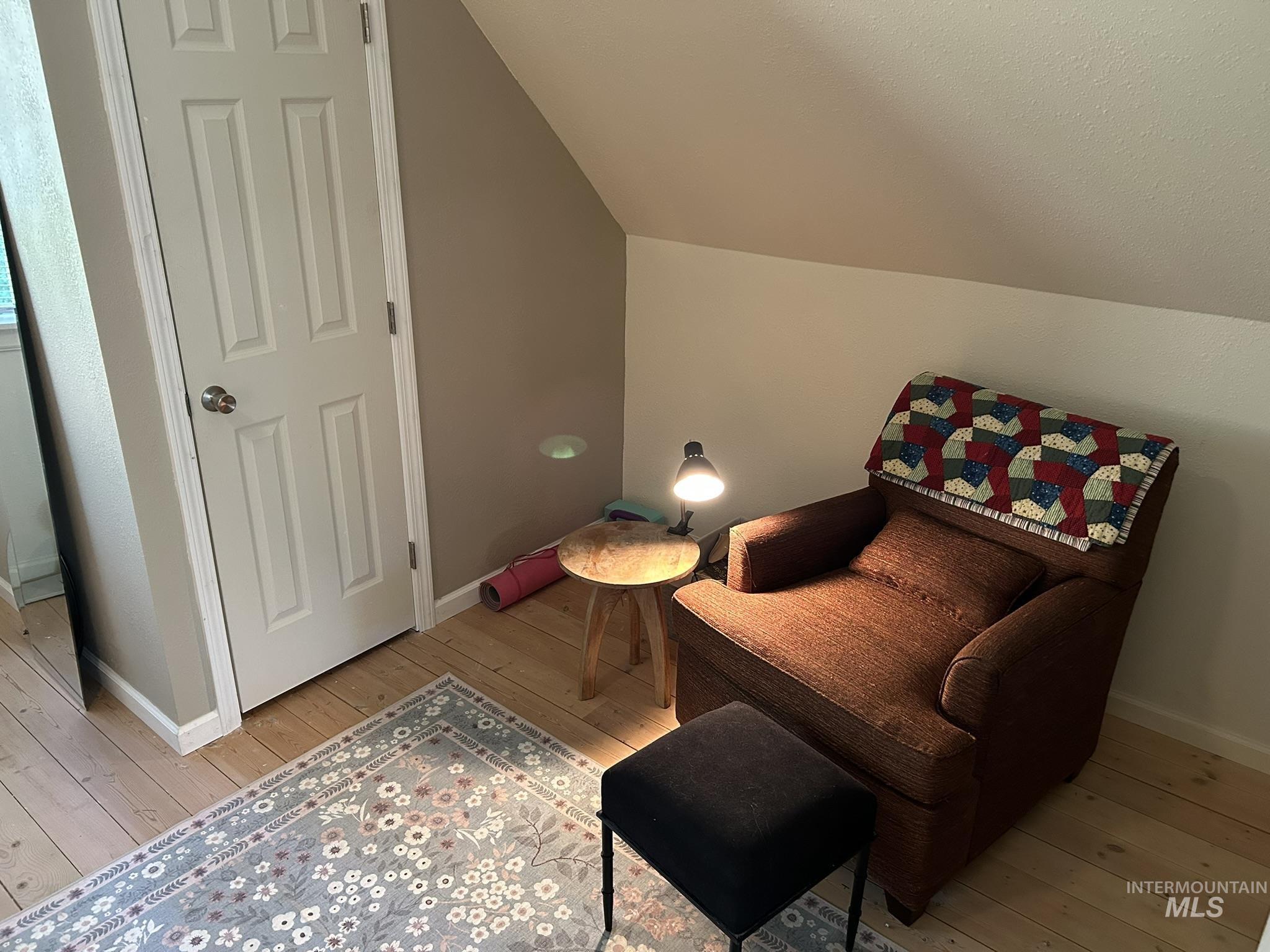 Living area with light wood-style floors and lofted ceiling