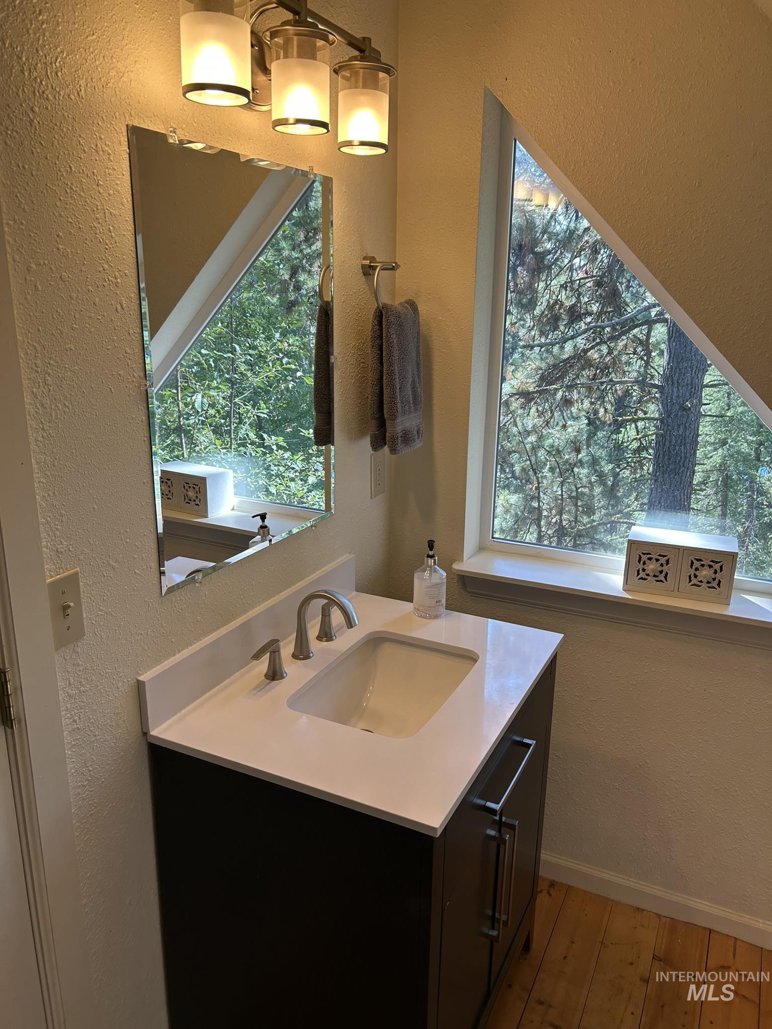 Bathroom featuring a textured wall, vanity, and light wood-style floors