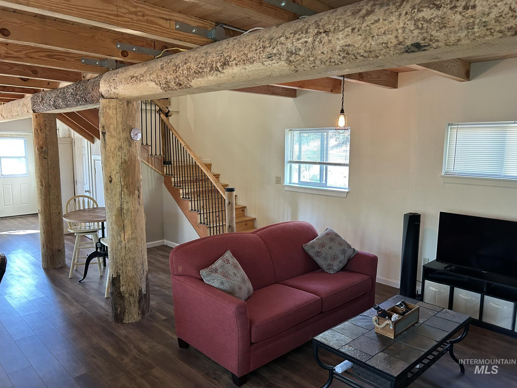 Living area with stairway, dark wood finished floors, and beam ceiling