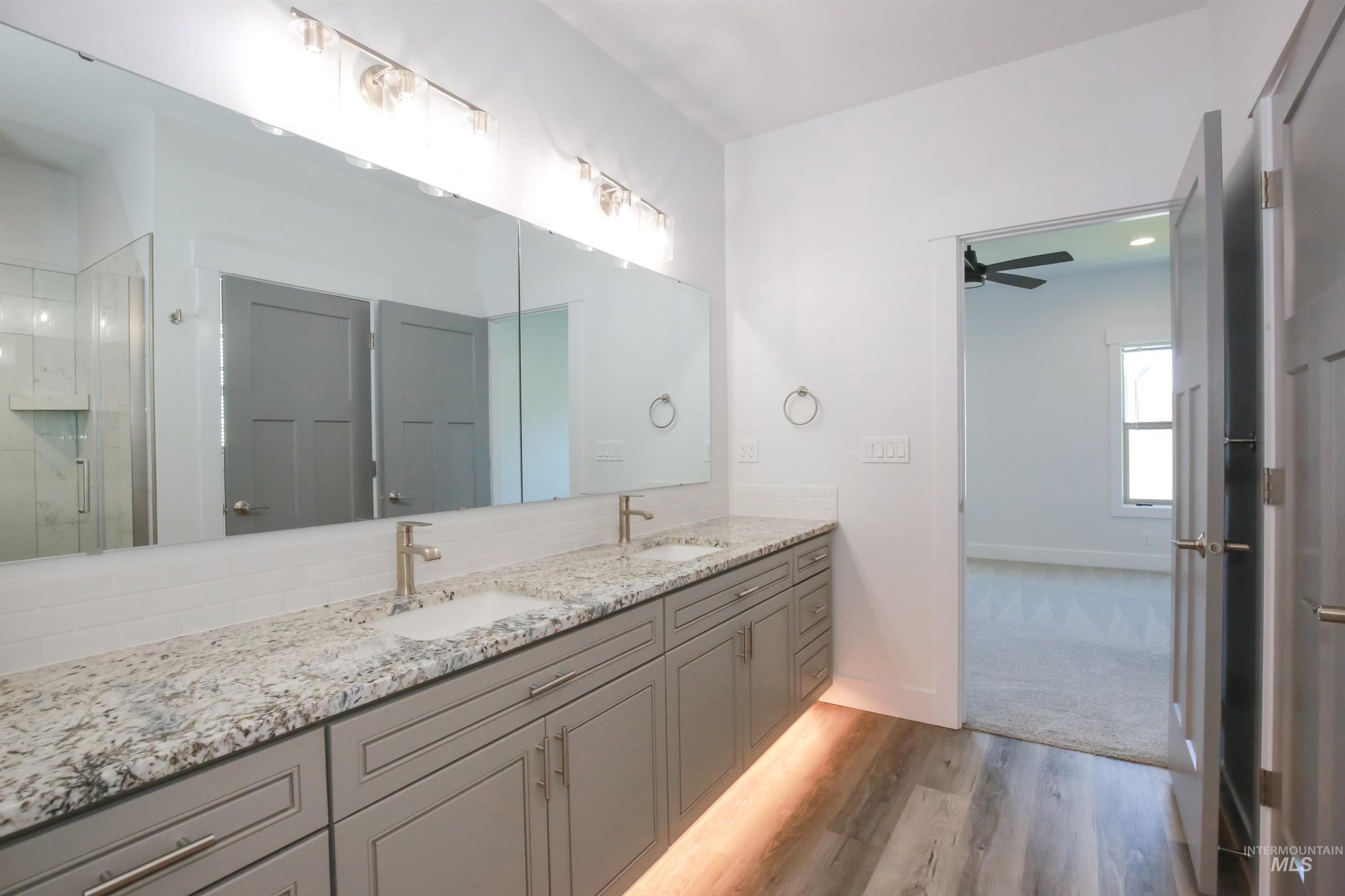 Bathroom with light wood-style floors, double vanity, a stall shower, and ceiling fan