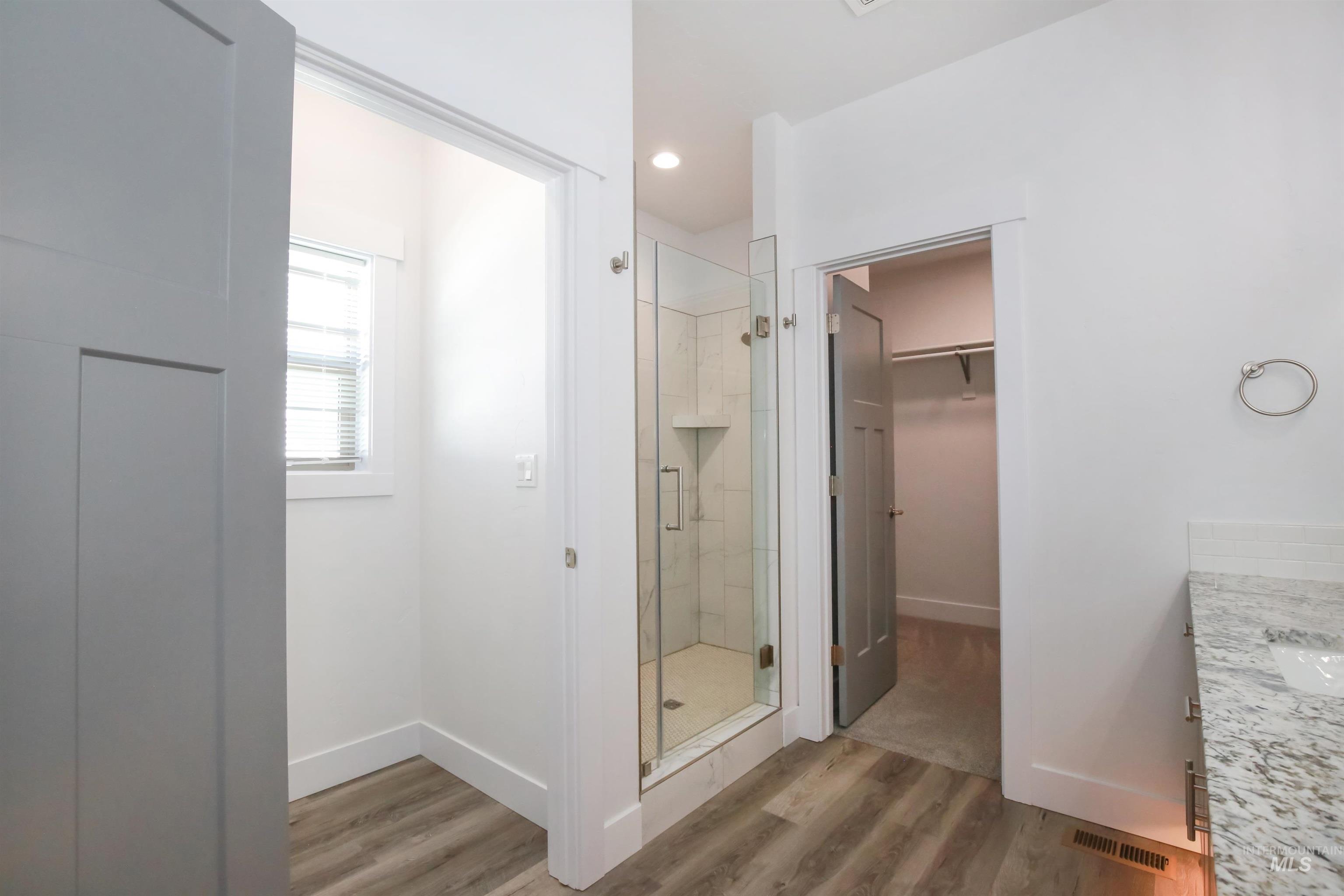 Full bathroom with a shower stall, light wood finished floors, vanity, a spacious closet, and recessed lighting
