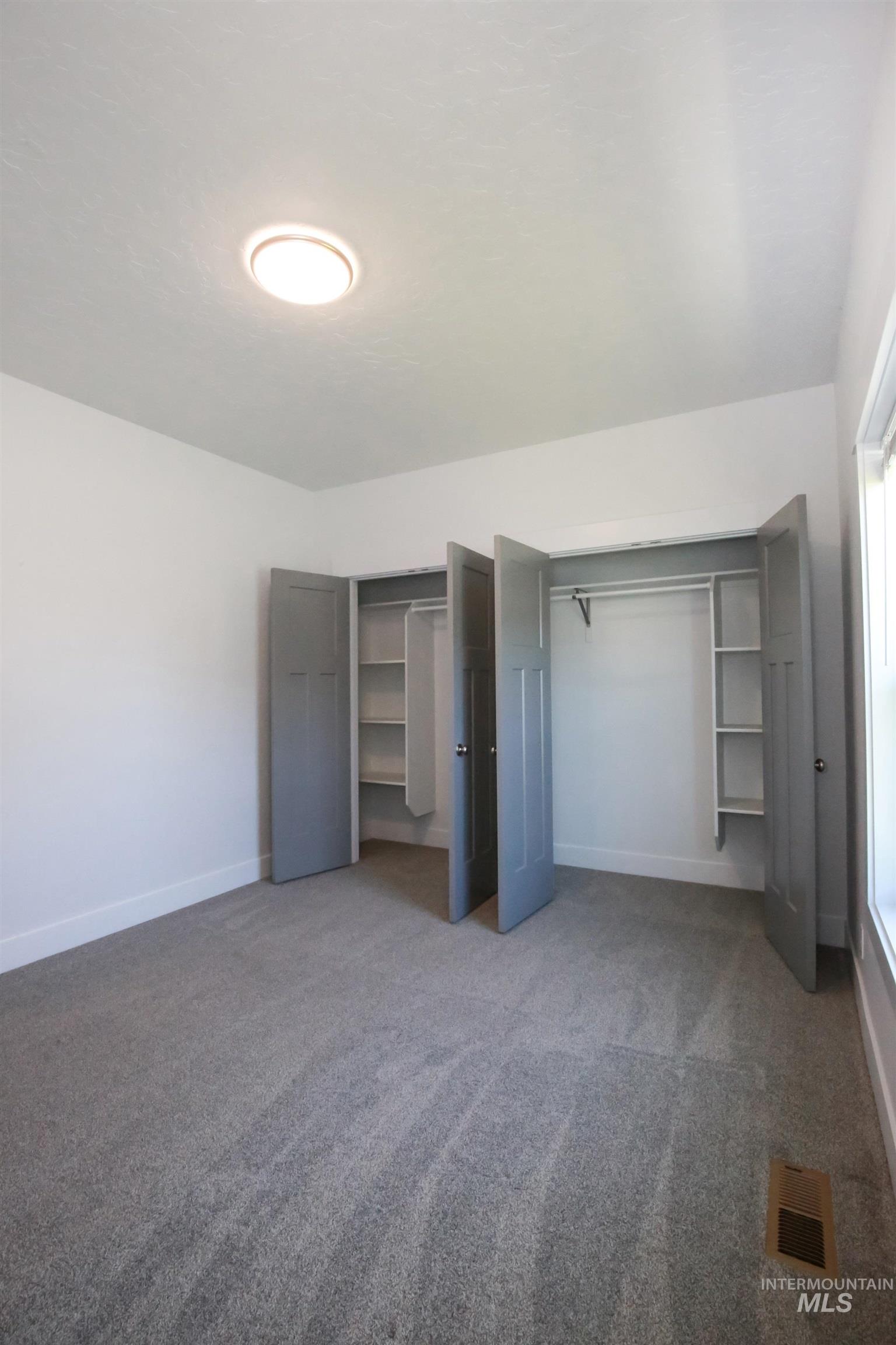 Unfurnished bedroom featuring multiple closets and carpet flooring