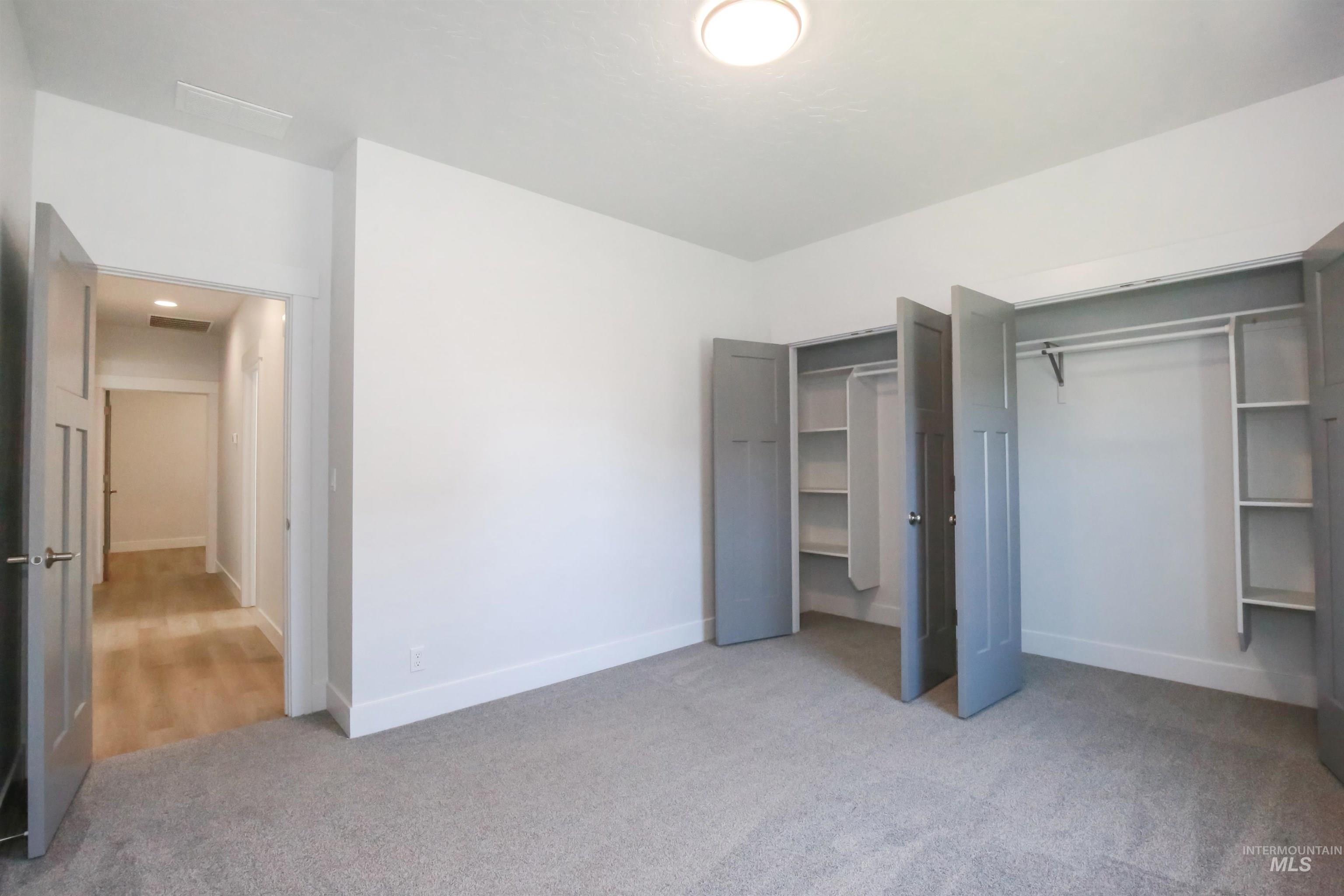 Unfurnished bedroom with light colored carpet and multiple closets