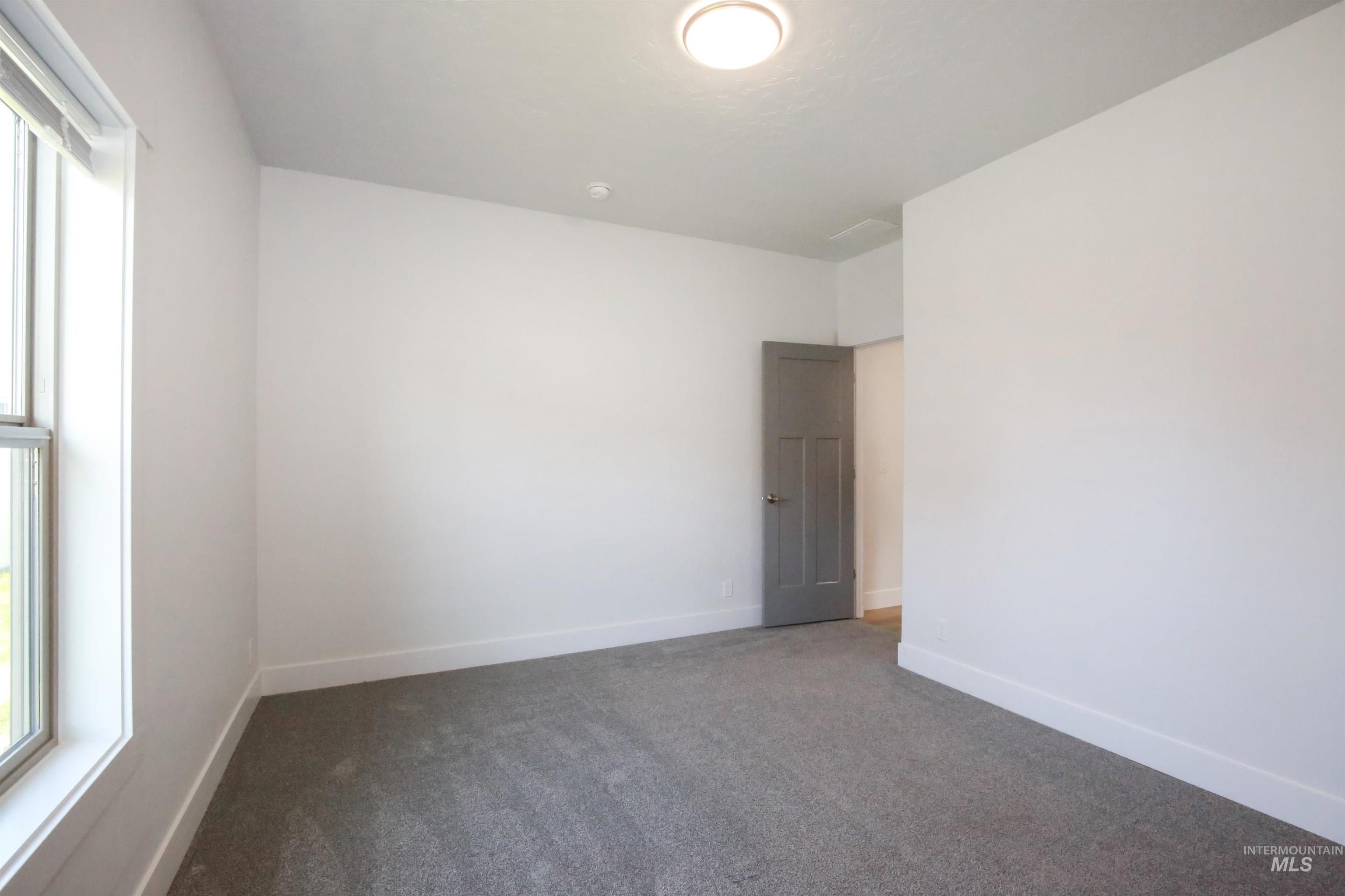 Carpeted spare room featuring baseboards