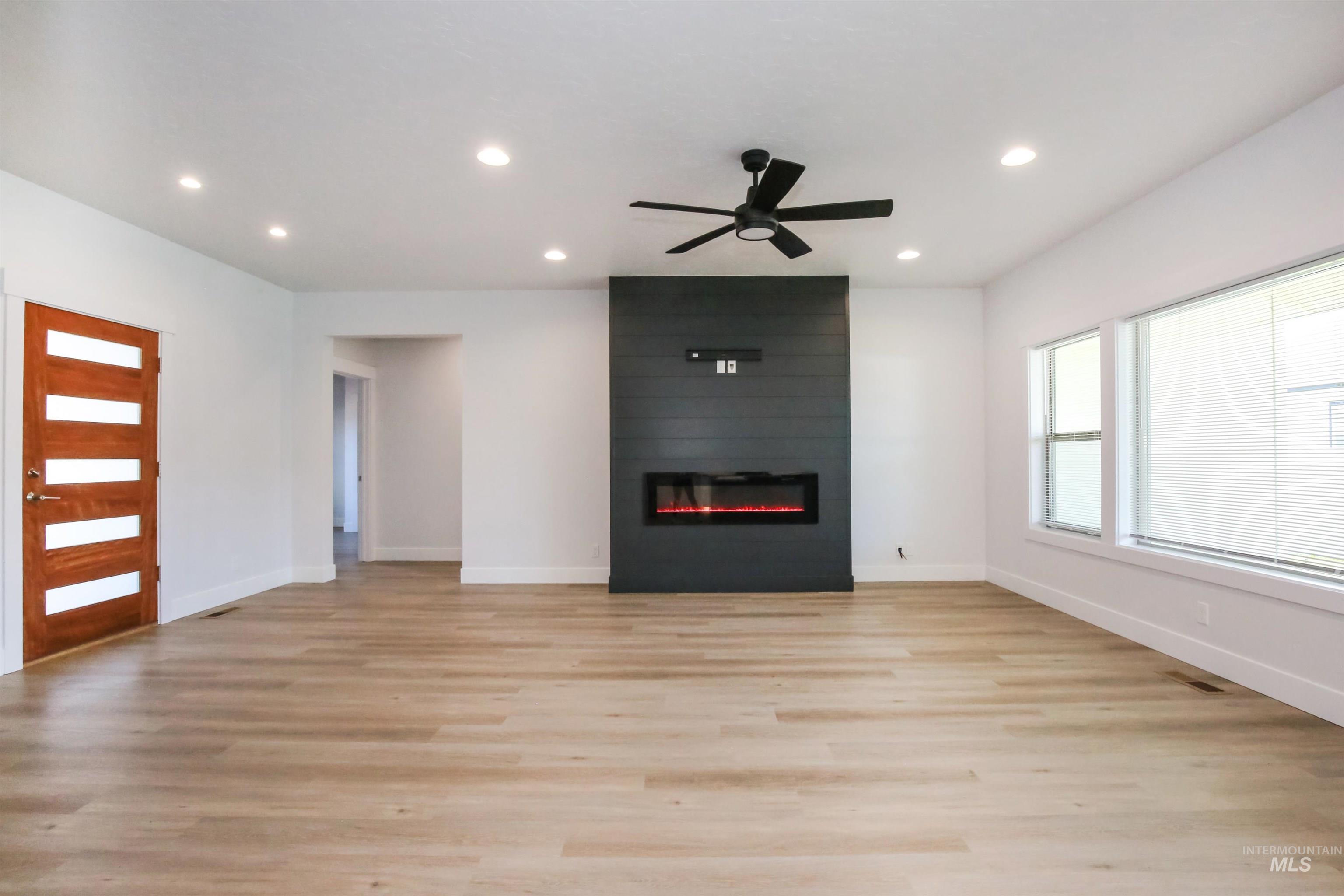 Unfurnished living room with light wood-type flooring, recessed lighting, a ceiling fan, and a large fireplace