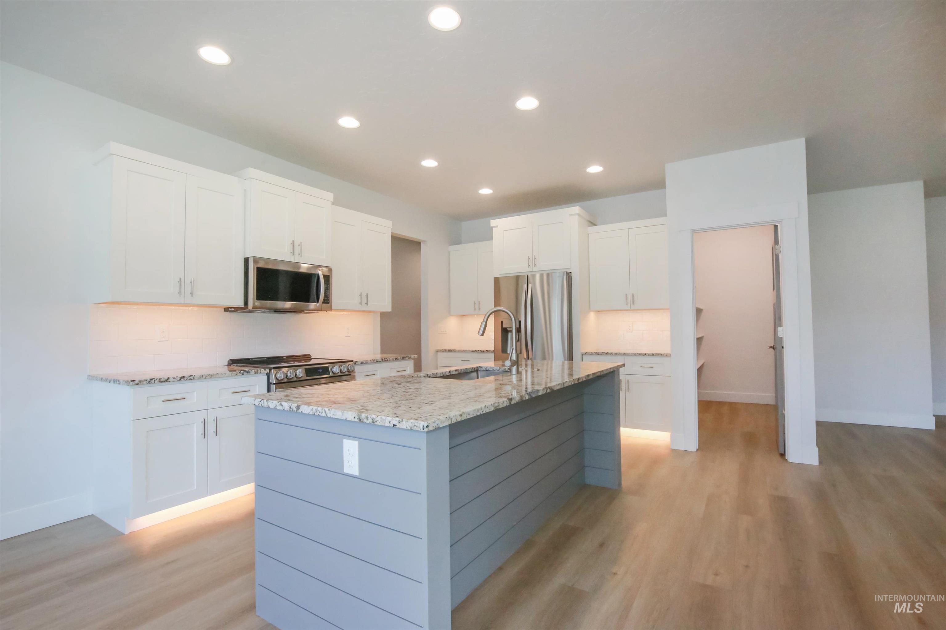 Kitchen with tasteful backsplash, white cabinets, recessed lighting, a kitchen island with sink, and stainless steel appliances