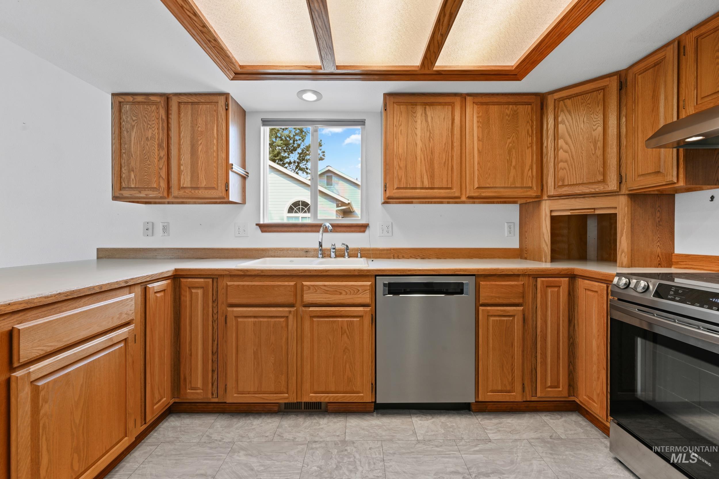 Kitchen featuring appliances with stainless steel finishes, brown cabinetry, and light countertops
