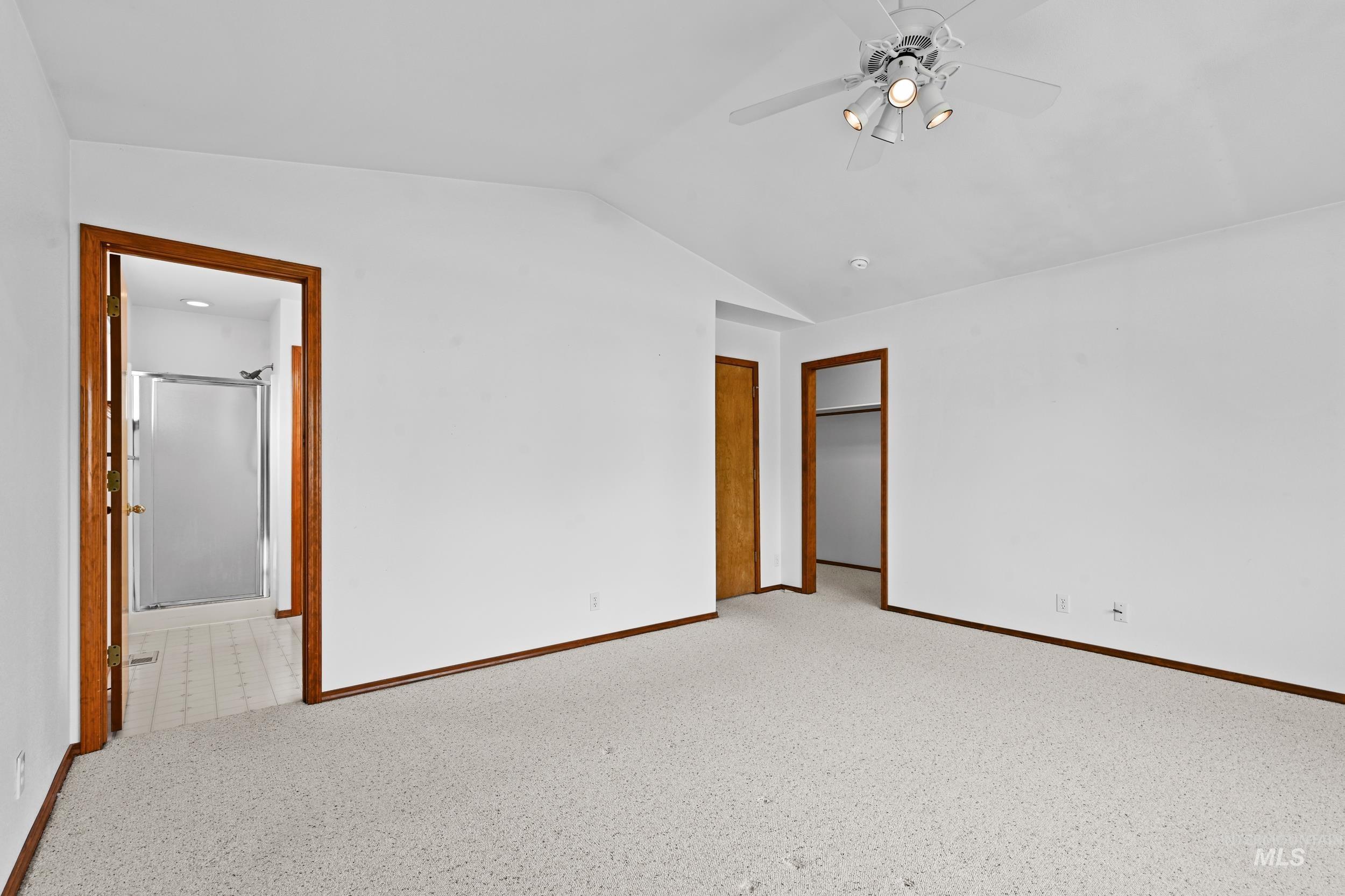 Unfurnished bedroom featuring carpet flooring, vaulted ceiling, a ceiling fan, and ensuite bathroom