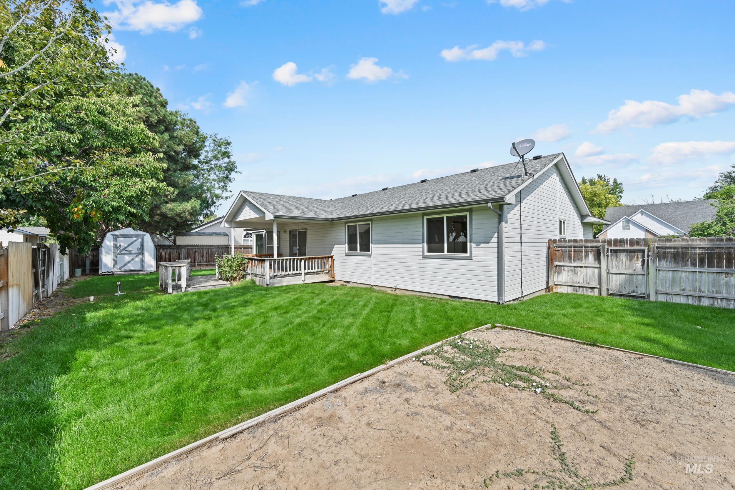 Rear view of property featuring a fenced backyard, a storage unit, a wooden deck, a shingled roof, and a gate