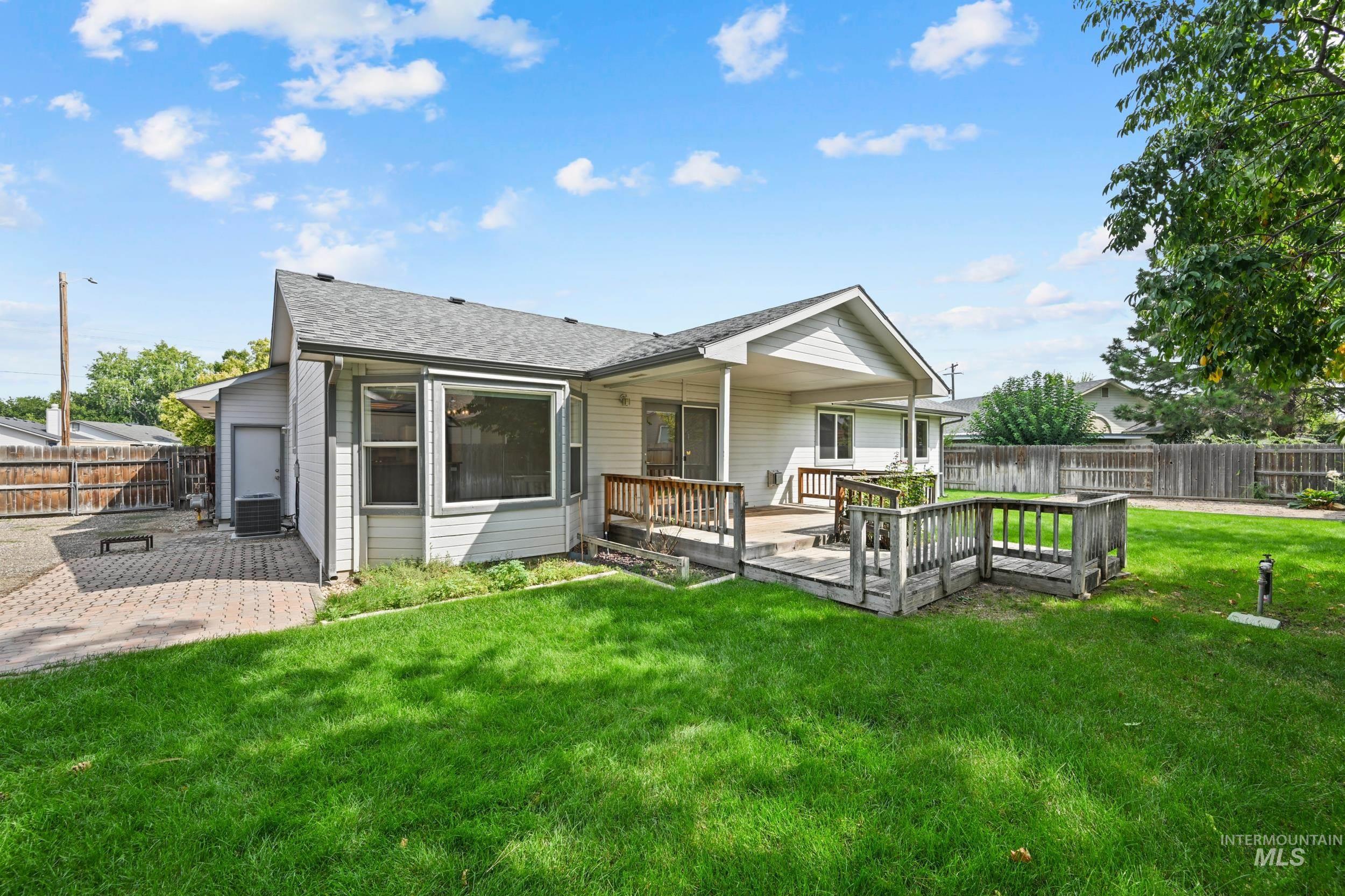 Rear view of house with a fenced backyard, a deck, and a shingled roof