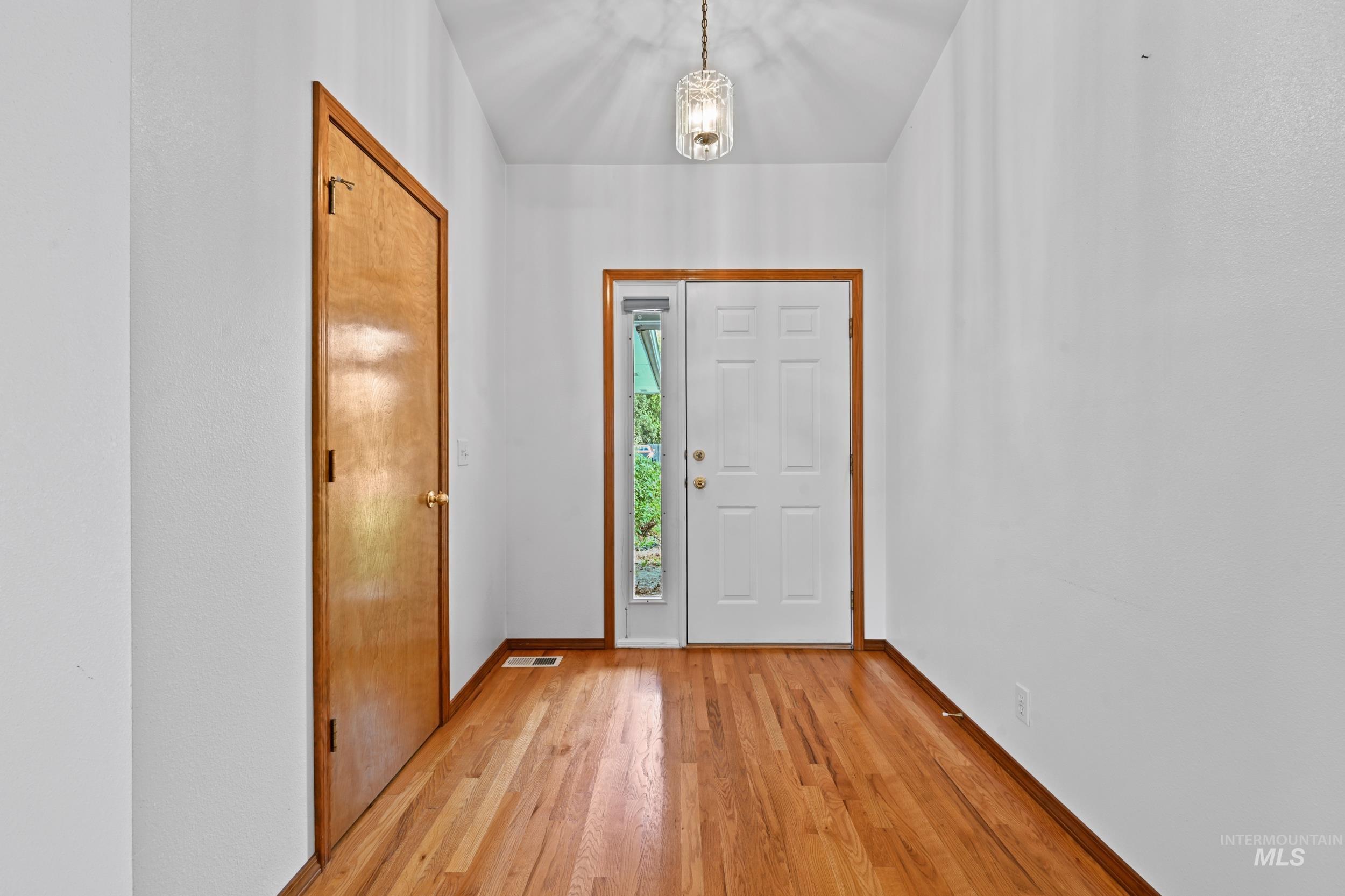 Entryway with wood finished floors and a chandelier