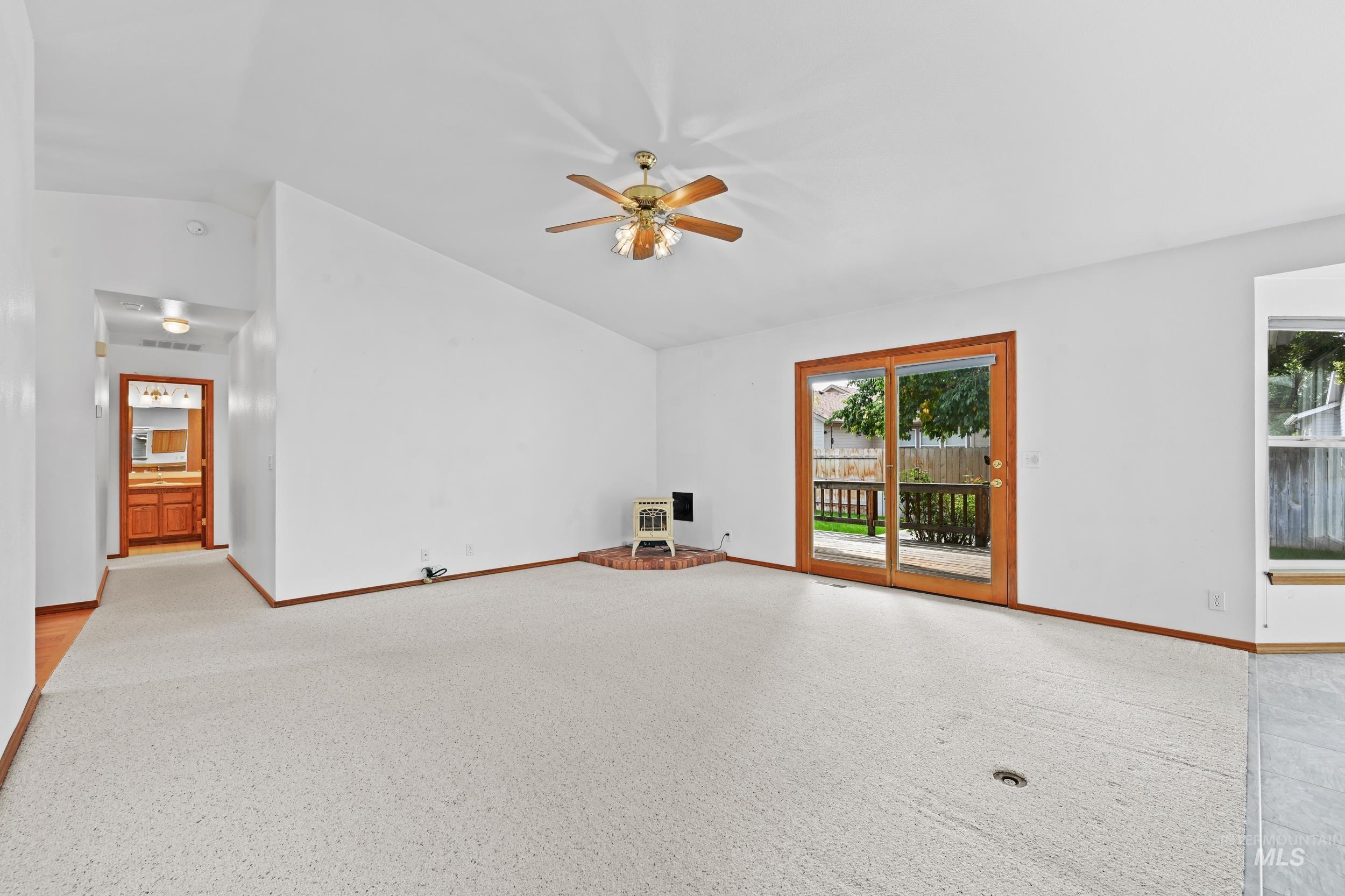 Unfurnished living room featuring lofted ceiling, ceiling fan, and heating unit