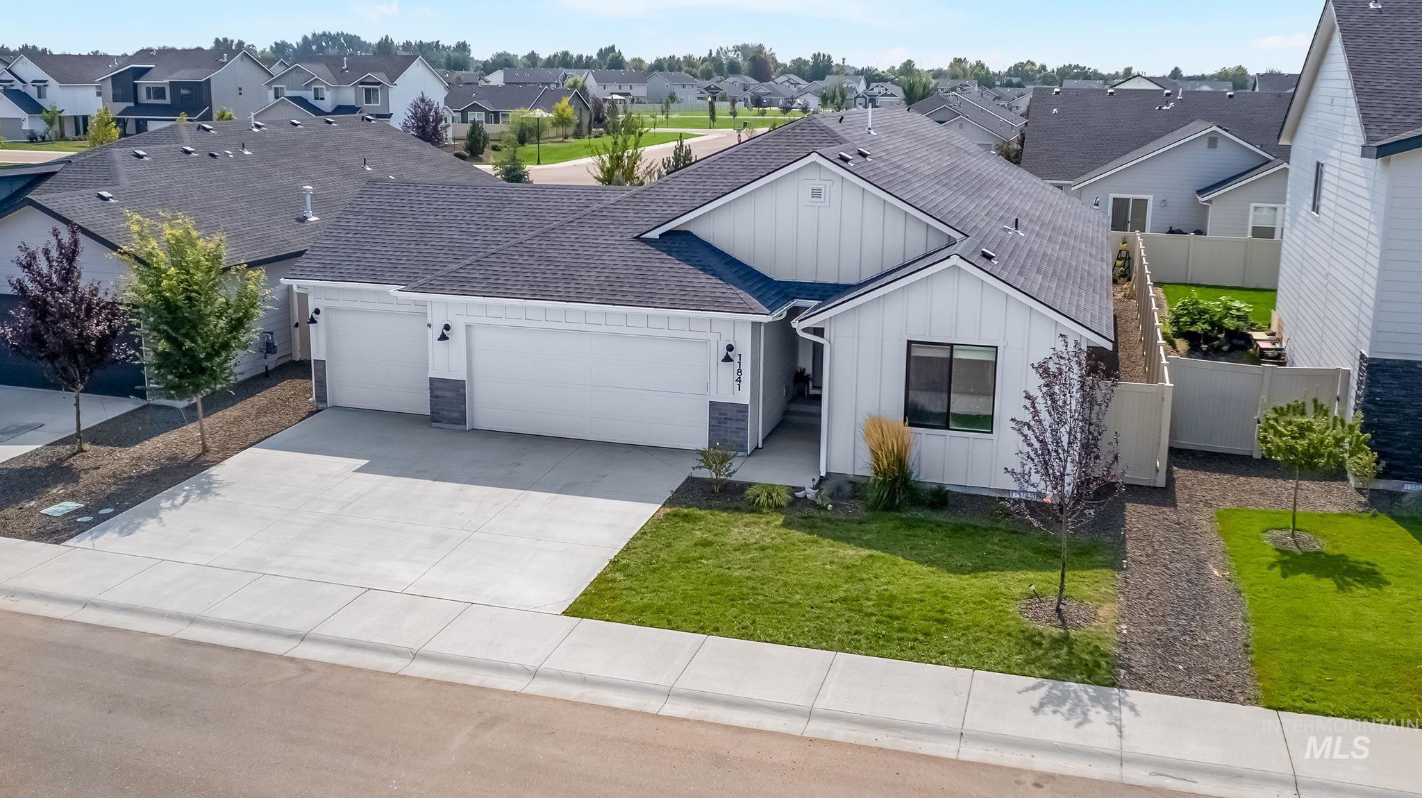 View of front of house featuring board and batten siding, an attached garage, a shingled roof, concrete driveway, and a residential view